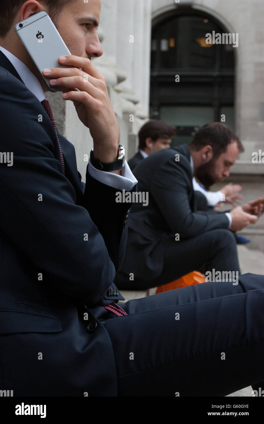 Pause déjeuner d'été dans le centre-ville de Londres s'asseoir sur les marches de travailleurs Royal Exchange de manger le déjeuner et l'utilisation de téléphone portable apple iphone Banque D'Images