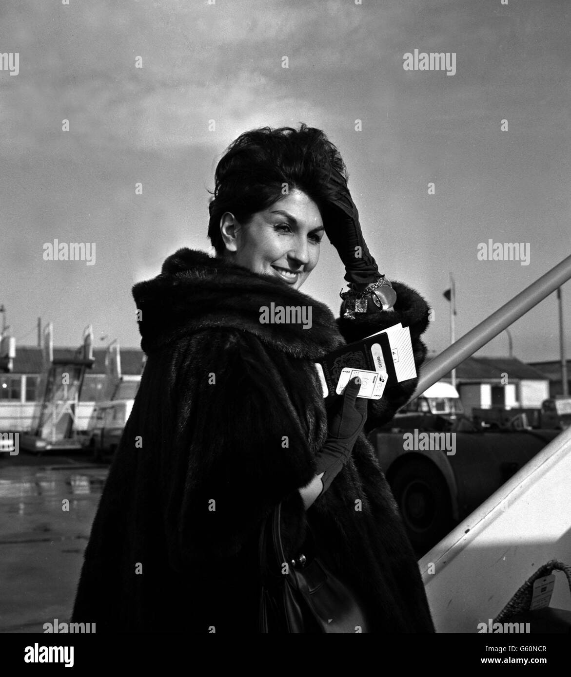 Le chanteur Alma Cogan, luttant contre le temps avec un luxueux manteau de fourrure, quitte l'aéroport de Londres pour New York. Banque D'Images