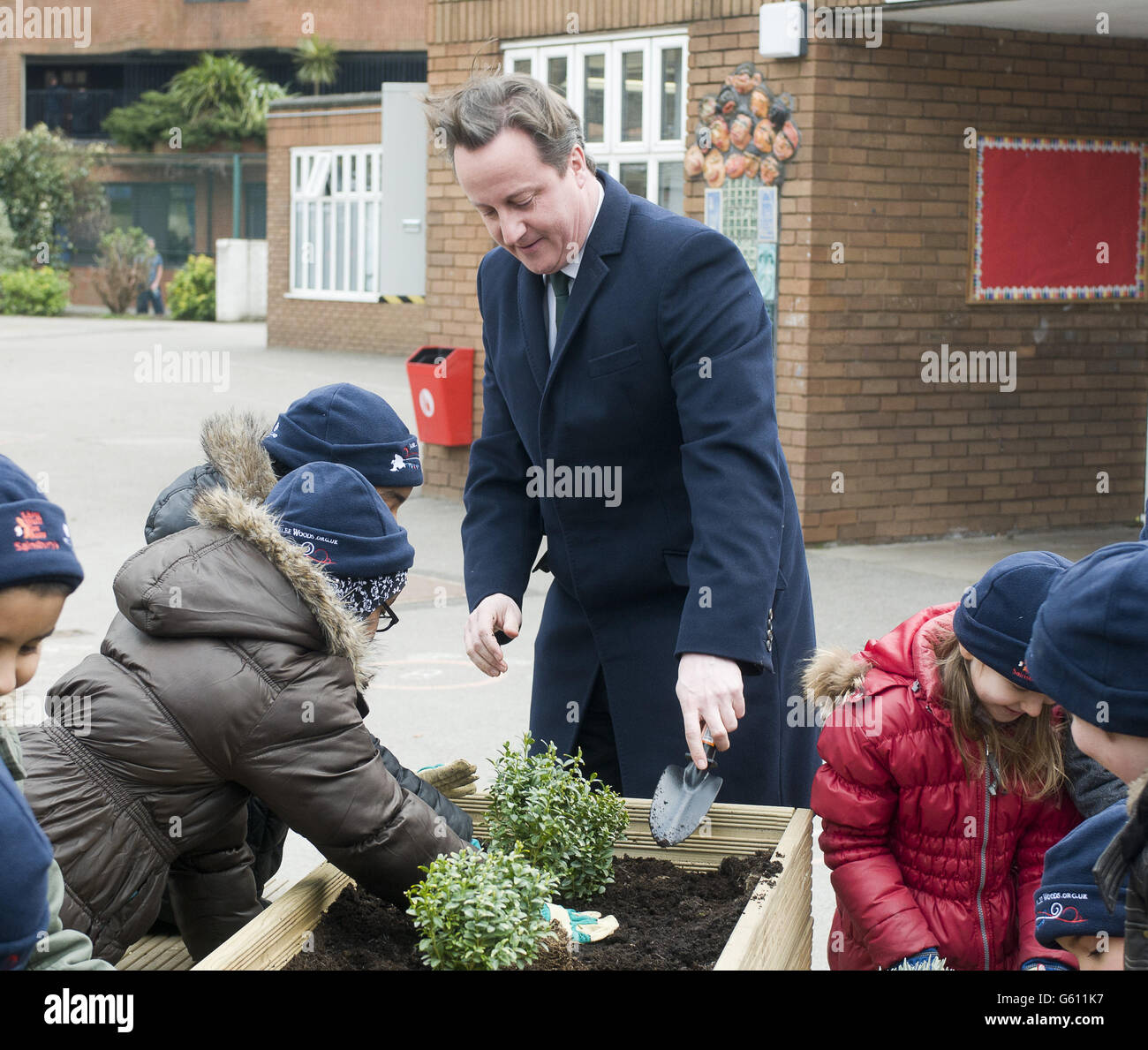 Le Premier ministre David Cameron, au centre, aide les écoliers à planter des arbustes en boîte lors d'une visite à l'école de la communauté d'Ashburnham, dans l'ouest de Londres. Banque D'Images