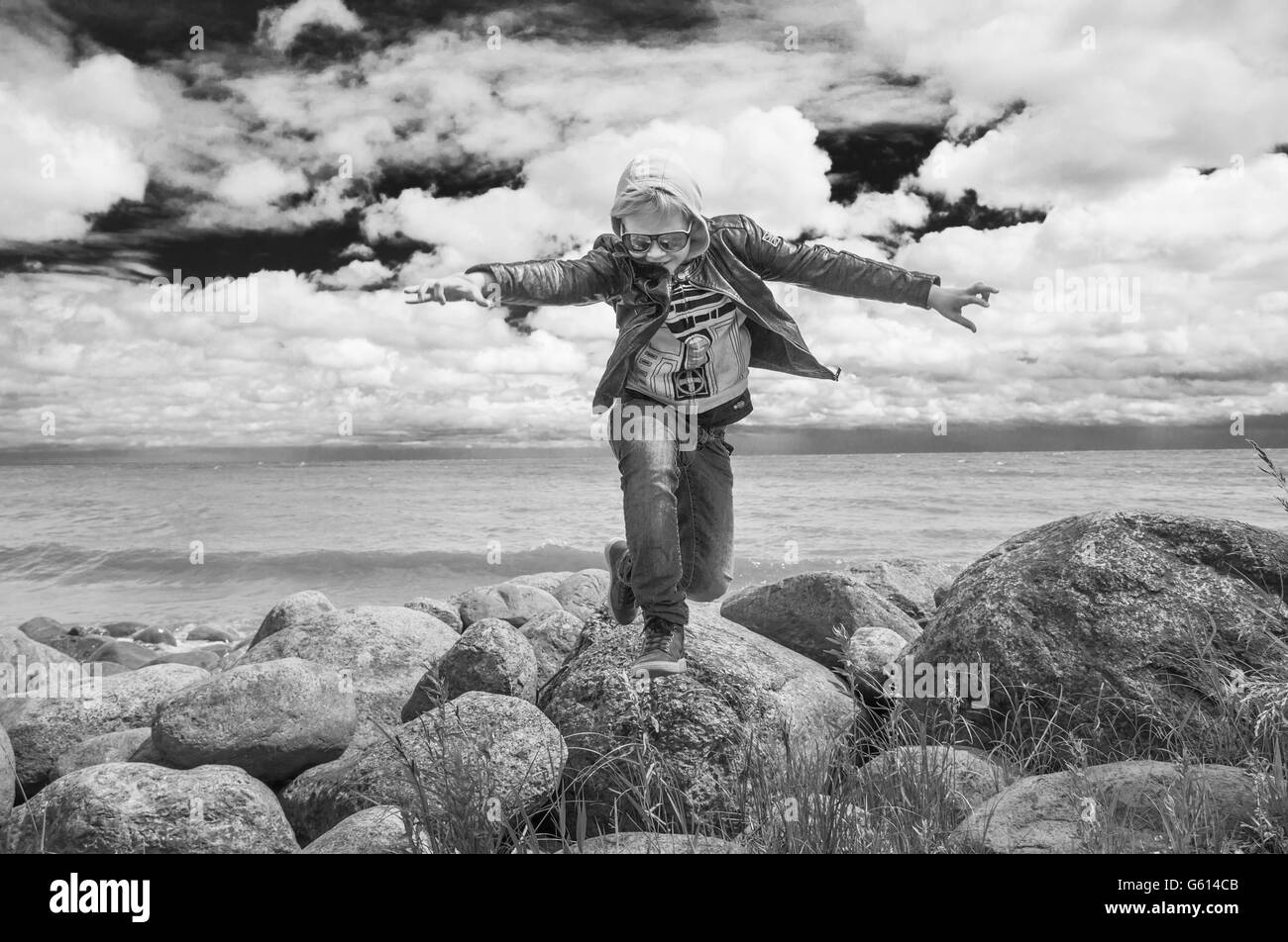 Un jeune garçon sautant sur les rochers près du lac Peipus, Estonie Banque D'Images