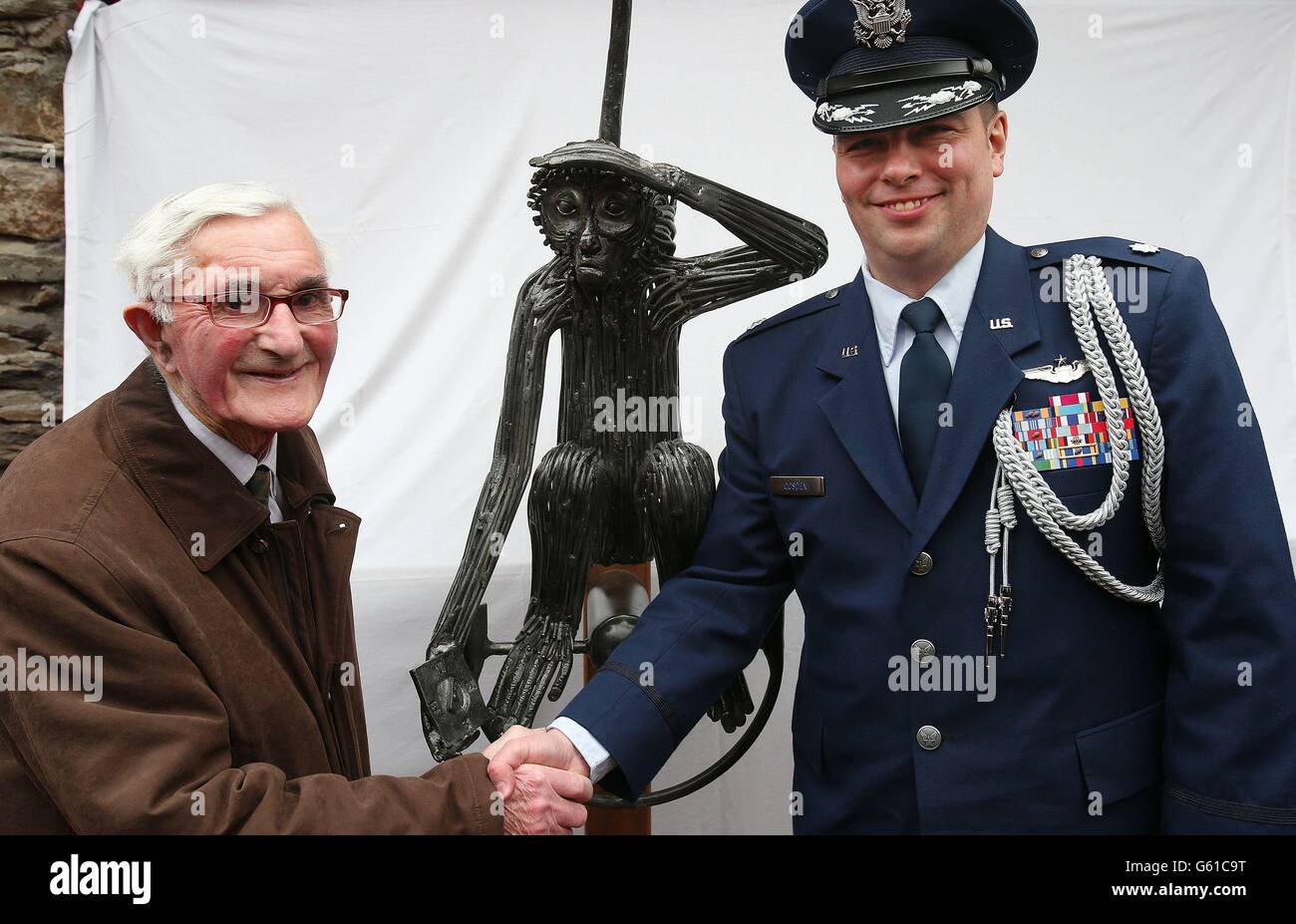 Ancien ingénieur de l'armée irlandaise de 93 ans, le soldat James Galvin (à gauche), Qui a posé la piste en 1943, avec le lieutenant-colonel Sean Cosden de l'Attache de la Défense américaine à l'hôtel O'Donovan à Clonakilty, à côté de la statue de 'Tojo', un singe appartenant à l'équipage d'un bombardier de l'Armée de l'Air américaine qui a écrasé leur Boeing B-17 Flying Fortress devant la ville le 7 avril 1943. Banque D'Images