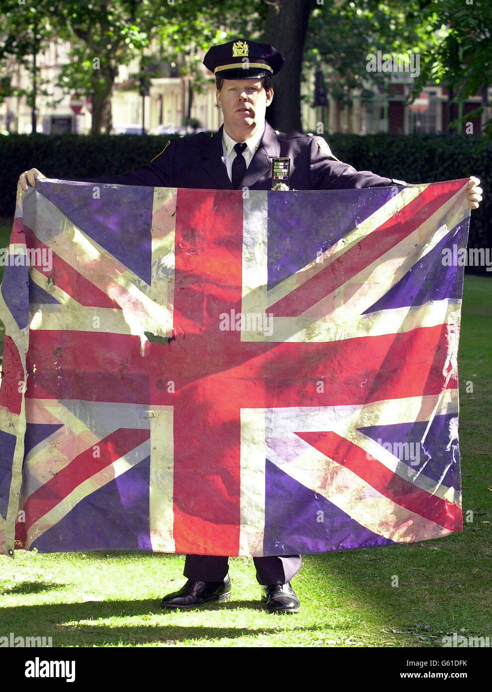 Le lieutenant Frank Dwyer, 40 ans, du département de police de New York détient un drapeau syndical qui a été trouvé dans les décombres du World Trade Center après les attaques terroristes de septembre 2001, à l'extérieur de l'ambassade des États-Unis dans le centre de Grosvenor Square à Londres. * le lieutenant présentera le drapeau au secrétaire à l'intérieur David Blunkett lors d'une cérémonie de souvenir dans la place demain pour marquer le premier anniversaire des atrocités aux États-Unis. Banque D'Images