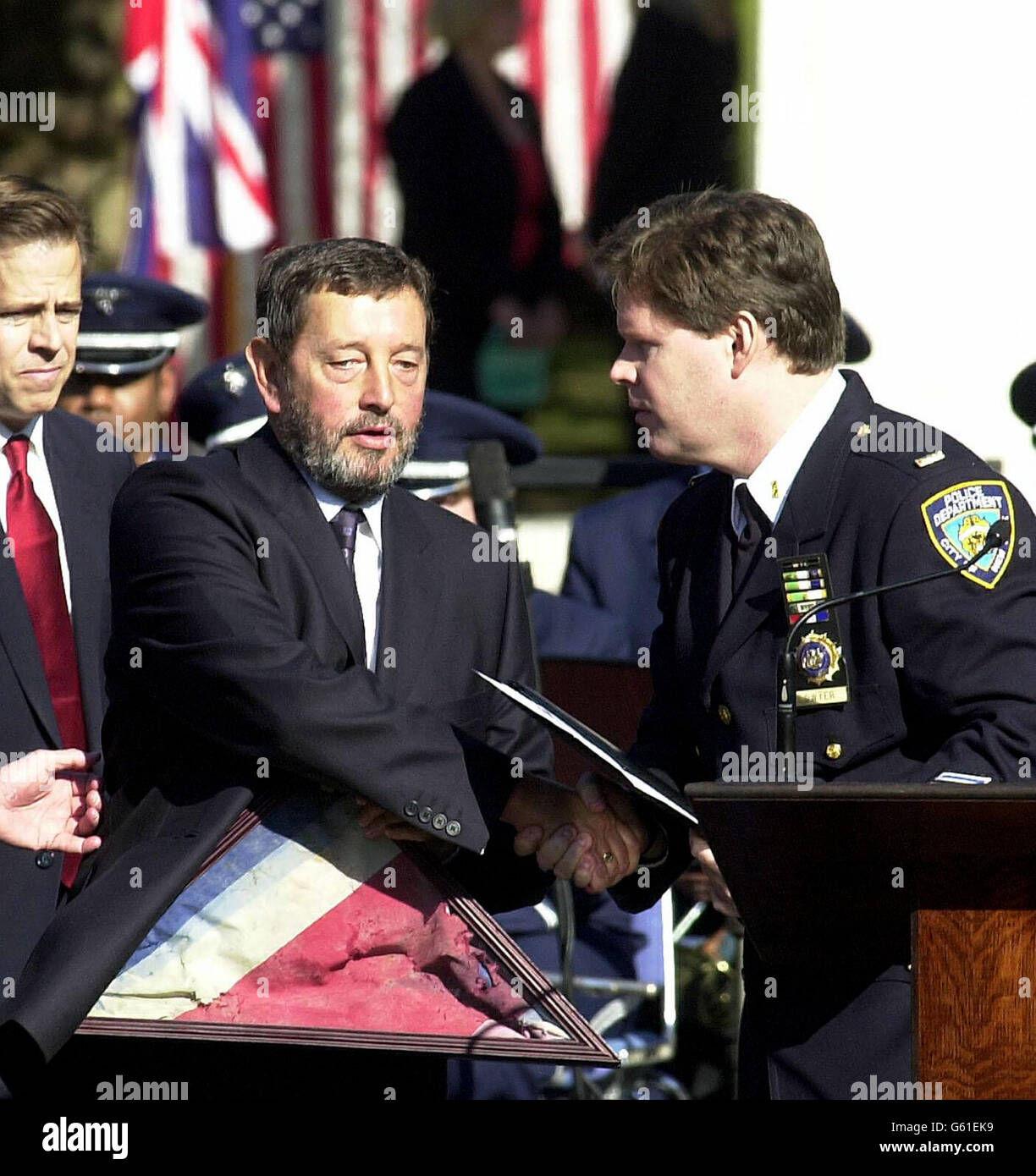 Le secrétaire d'État David Blunkett reçoit un drapeau de l'Union récupéré au Ground Zero du lieutenant Frank Dwyer du département de police de New York lors d'une cérémonie devant l'ambassade américaine sur la place Grosvenor à Londres. *..... de se souvenir de ceux qui sont morts il y a un an dans des attaques terroristes sur New York, Washington et Pennsylvanie. Ailleurs, le prince de Galles, le prince Harry, le premier ministre et d'autres personnalités du pays assistaient à un service de commémoration à la cathédrale Saint-Paul. Banque D'Images