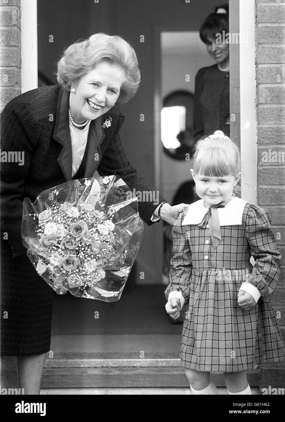La première ministre, Mme Margaret Thatcher, présente Alex Gater, quatre ans, aux caméras après avoir reçu un bouquet de fleurs de la petite fille lors d'une visite à la maison de ses parents dans le cadre du programme de logement de St Hildas à Middlesborough. Banque D'Images