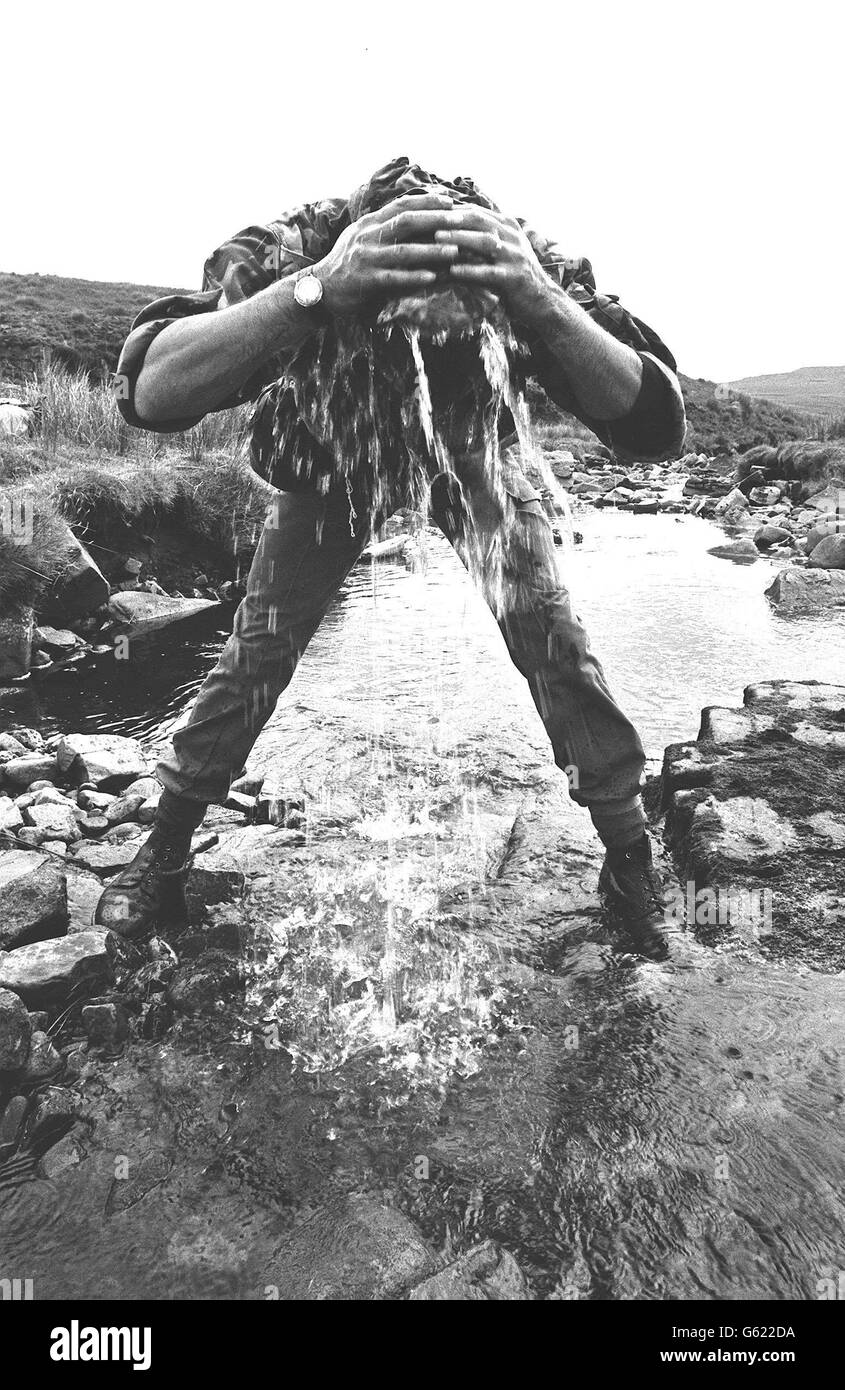 Une recrue SAS se rafraîchit avec une hatfull d'eau d'un ruisseau de montagne pendant l'entraînement d'endurance à travers le pays. Banque D'Images
