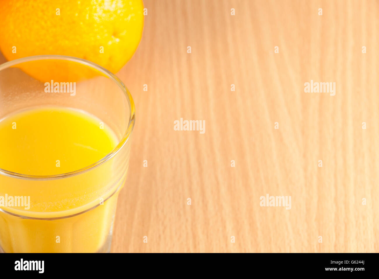 Tout frais mûrs orange et un verre de jus d'orange sur une table de petit déjeuner en bois Banque D'Images