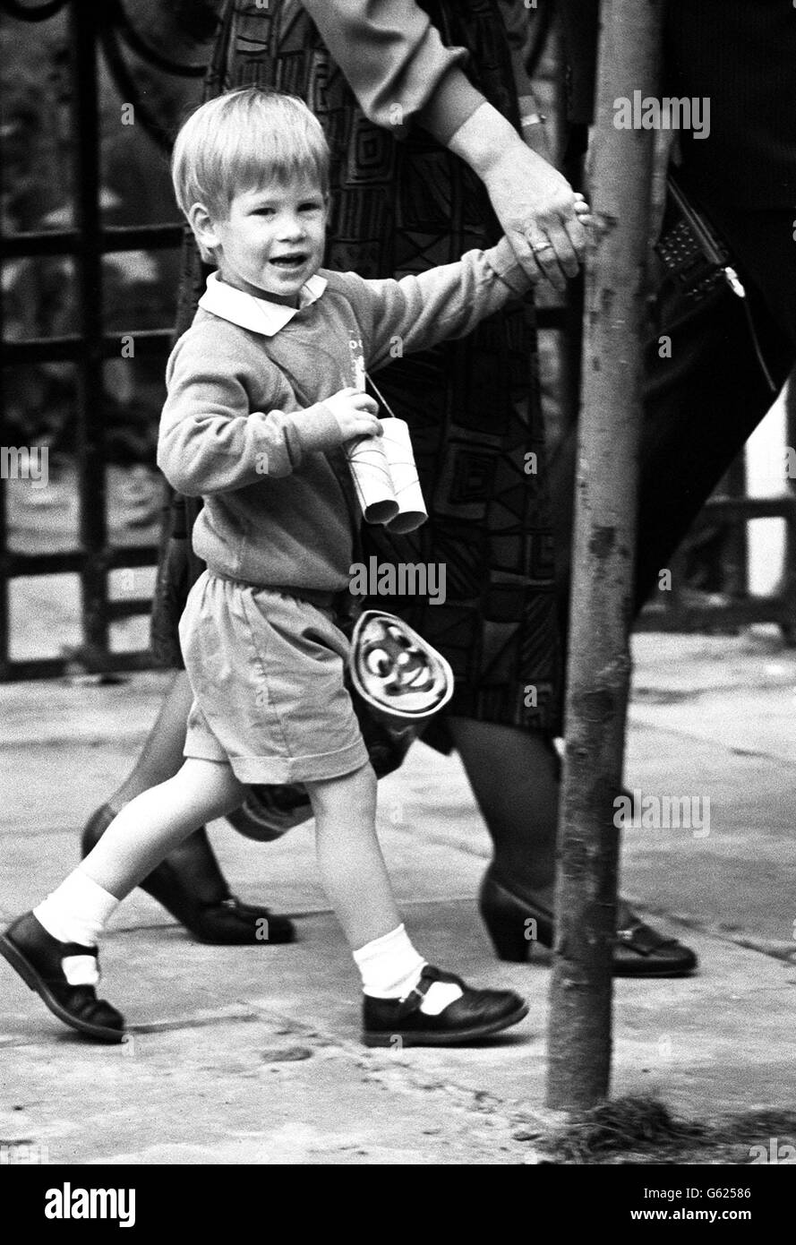 Le prince Harry, fils de trois ans du prince et de la princesse de Galles, quitte son jardin d'enfants ce matin en accrochant ses efforts du premier matin -- une paire de jumelles faites de deux rouleaux de toilettes. Banque D'Images