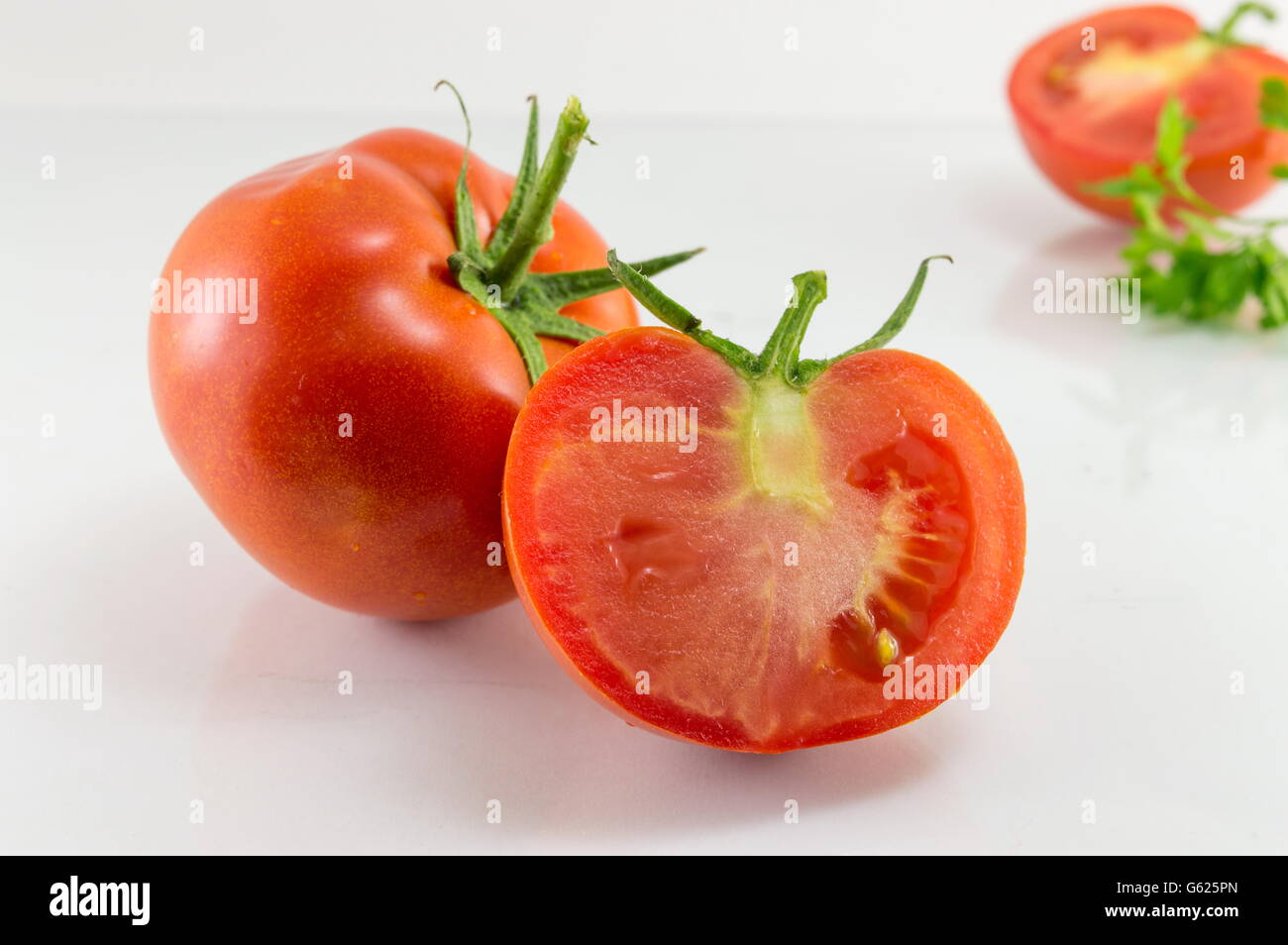 Tranches de tomate fraîche sur une planche de bois blanc Banque D'Images