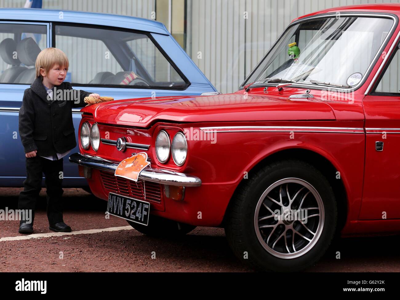 Zach Stuart, un passionné de voitures de quatre ans, polit un Imp Hillman alors que les voitures se préparent à quitter en convoi le site de l'ancienne usine de Linwood pour marquer le 50e anniversaire de la première Imp Hillman fabriquée à l'usine de Rootes. Banque D'Images