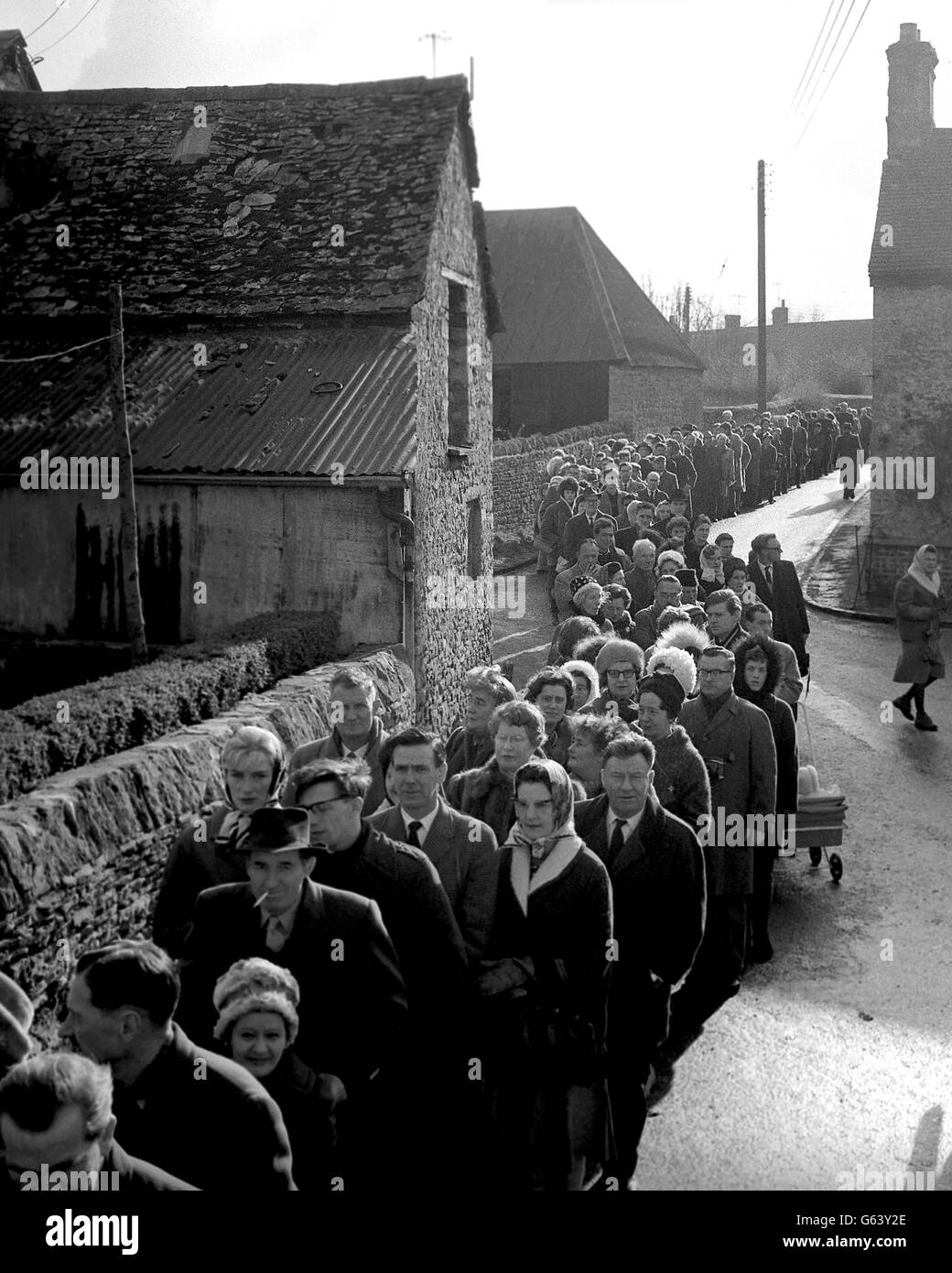 Une file d'attente de trois ou quatre profondément dans des endroits serpente à travers les bâtiments du village de Bladon, Oxfordshire, quand des milliers sont arrivés en voiture pour déposer silencieusement devant la tombe de Sir Winston Churchill dans le cimetière de Bladon. Banque D'Images