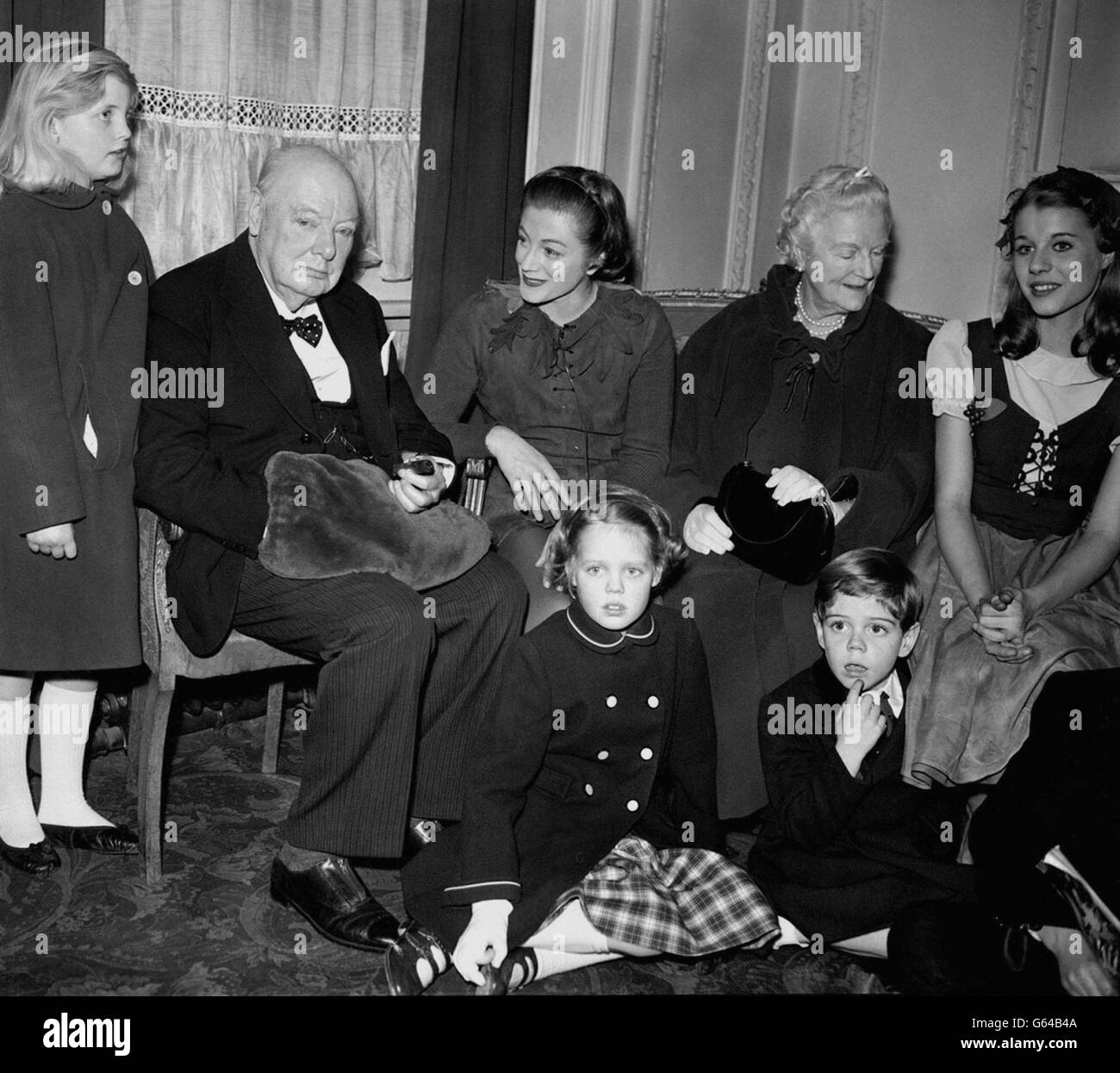 Sir Winston Churchill, Lady Churchill et une fête de famille après avoir assisté à une représentation de Peter Pan dans laquelle la fille de l'actrice de Churchill, Sarah, au centre, toujours en costume, joue Peter.Autour de Sir Winston et de Lady Churchill se trouvent trois de leurs petits-enfants, Arabella (à gauche), et Emma et Jeremy Soames.À droite de Lady Churchill se trouve Julia Lockwood, qui joue Wendy. Banque D'Images