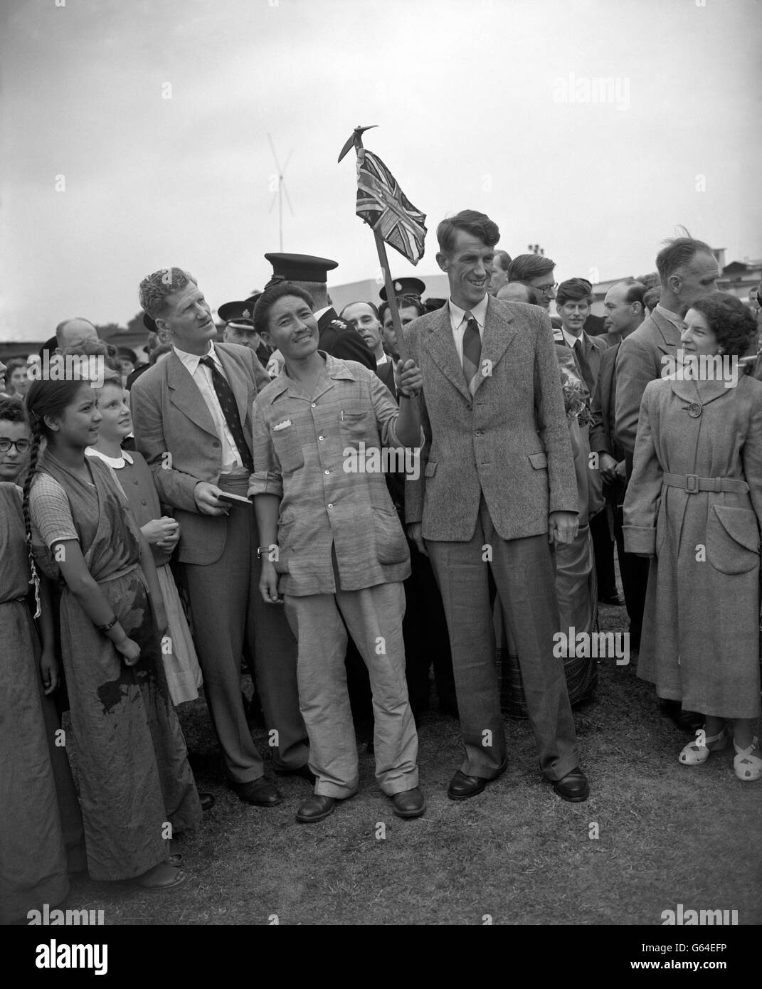 L'Everest conquérant Edmund Hillary (à droite), de Nouvelle-Zélande, et Sherpa Tensing Norkey, qui signe un drapeau de l'Union, sont descendus d'un avion de ligne de la BOAC pour rejoindre l'un des plus grands lieux d'accueil de l'aéroport de Londres.Avec eux se trouvaient le colonel John Hunt, chef de l'expédition britannique, et d'autres membres du parti à leur retour après avoir finalement atteint le sommet de l'Everest, la plus haute montagne du monde. Banque D'Images
