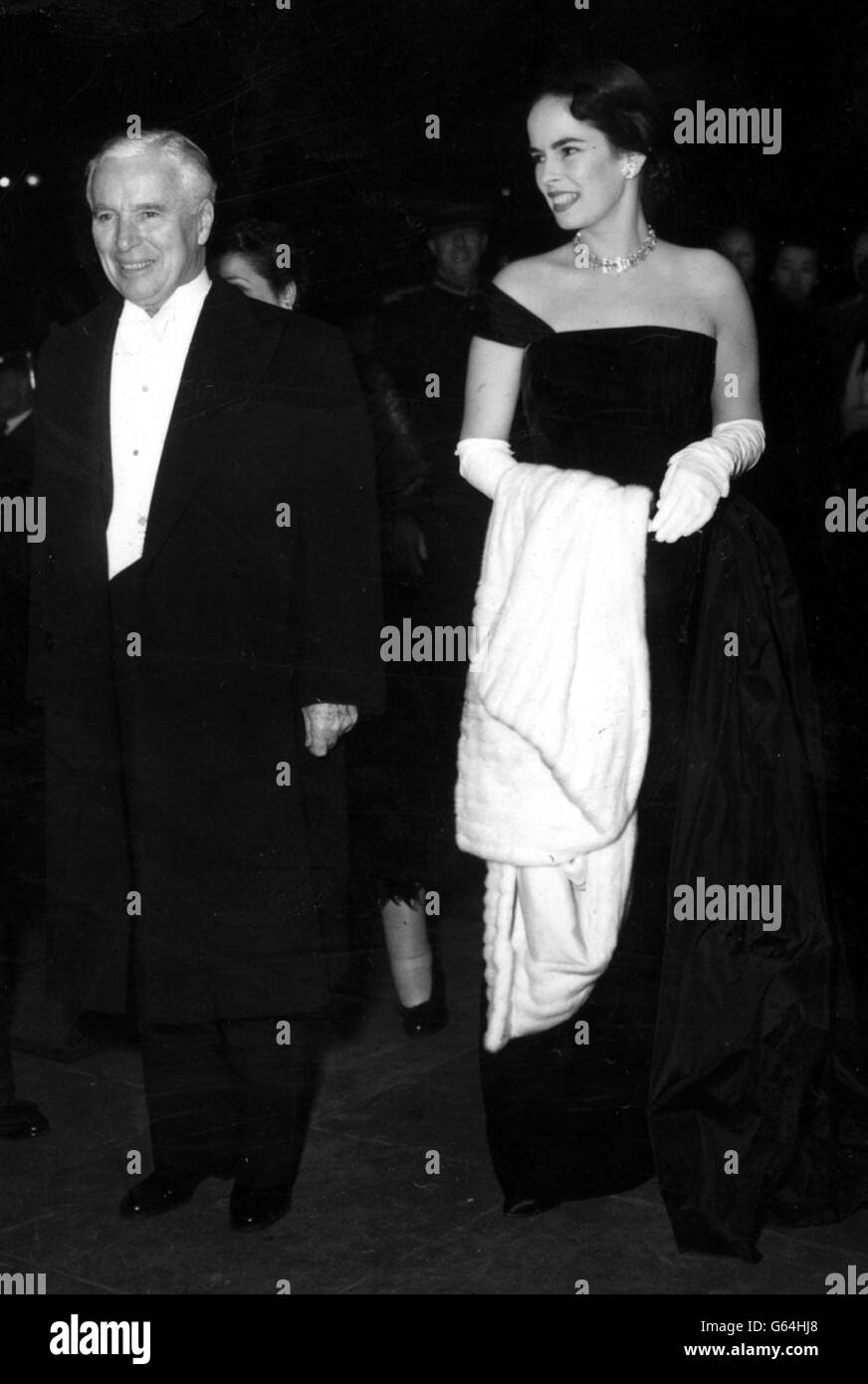 Charlie Chaplin et son épouse, Oona - avec une cape à fourrure au-dessus de son bras - arrivent pour le Royal film Show à l'Empire Theatre, Leicester Square. Chaplin devait faire une apparition devant la Reine et d'autres membres de la famille royale. Banque D'Images