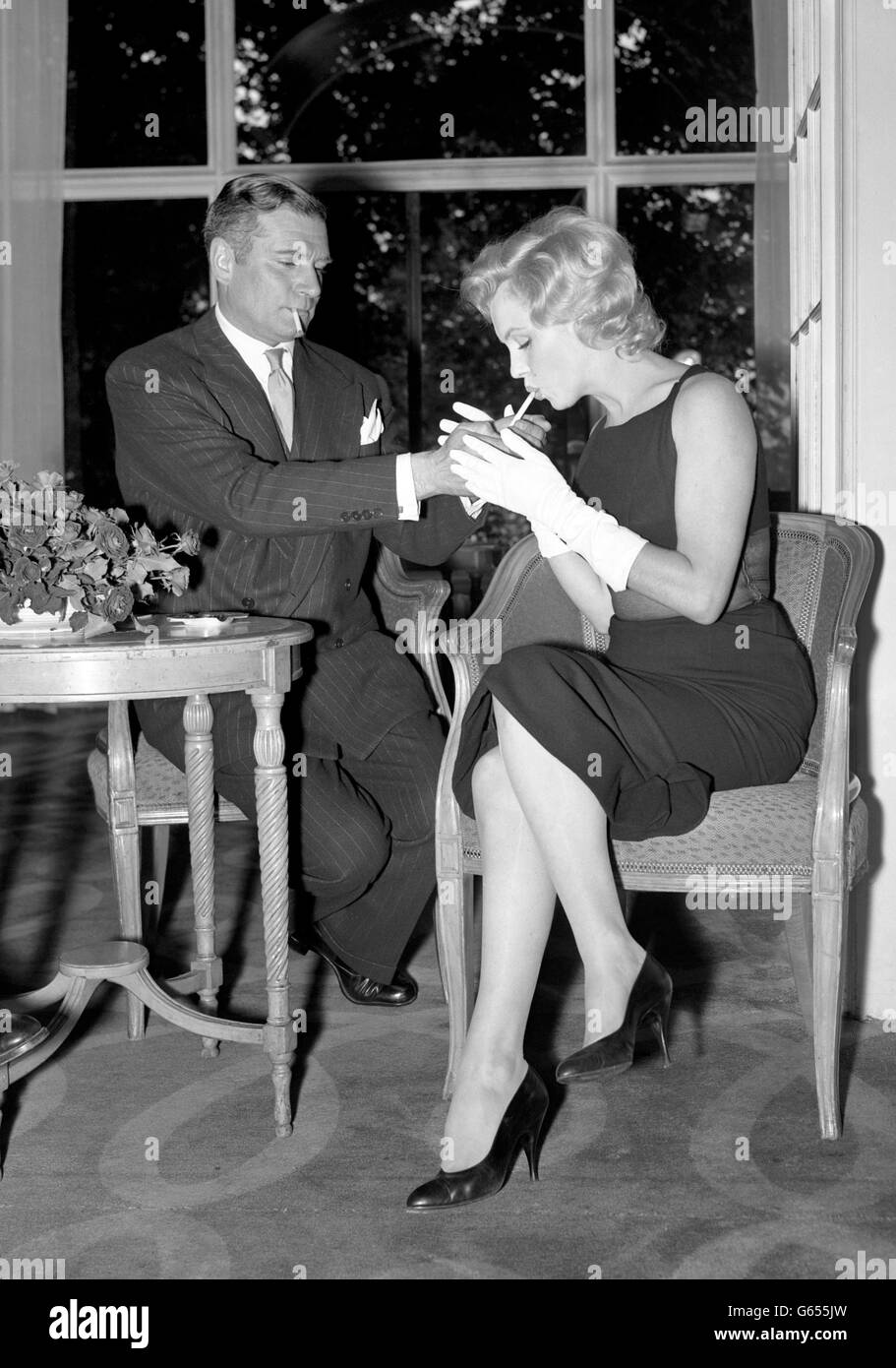 L'actrice du film hollywoodien Marilyn Monroe se penche pour obtenir une lumière pour sa cigarette de sa nouvelle co-star, Sir Laurence Olivier, en Grande-Bretagne, lors d'une conférence de presse qu'elle a donnée à l'Hôtel Savoy, Strand. Banque D'Images