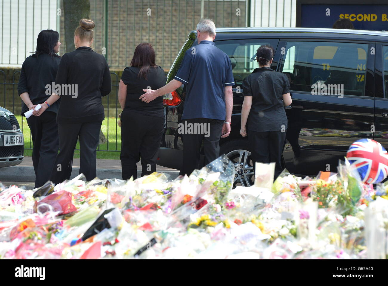 Les membres de la famille du batteur Lee Rigby partent après avoir regardé les hommages floraux à l'extérieur de Woolwich Barracks lorsqu'ils ont visité la scène de son meurtre à Woolwich, dans le sud-est de Londres. Banque D'Images