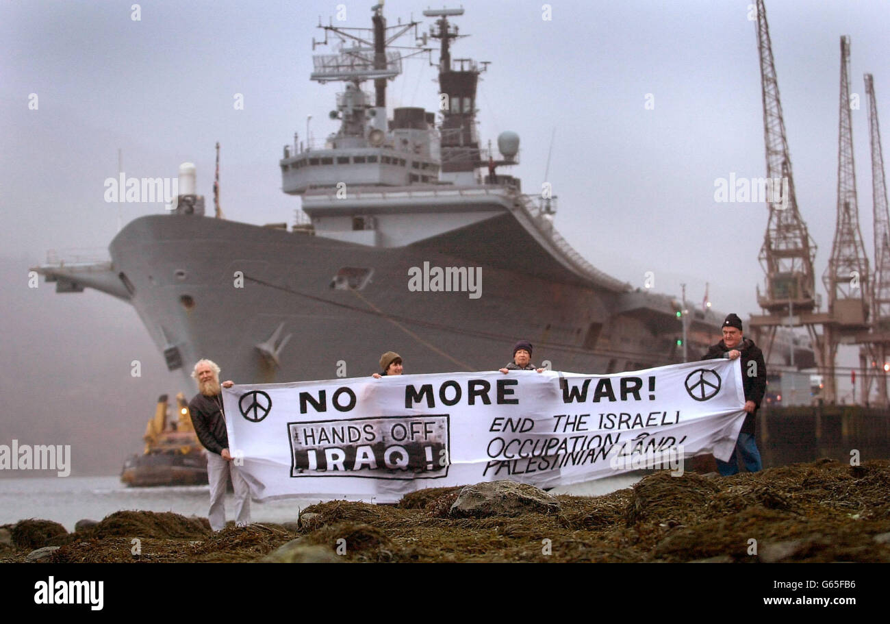 Des manifestants anti-guerre manifestent sur la rive, à côté du porte-avions britannique HMS Ark Royal, sur le Loch long, à l'usine de munitions de Glen Douglas, en Écosse.*..l'Ark Royal y prendra des magasins avant de partir sur un déploiement qui l'emportera à la Méditerranée et peut-être sur le golfe. Banque D'Images