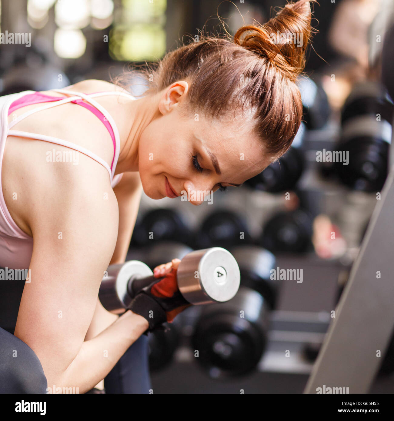 Jeune femme confiante biceps faisant de l'exercice avec haltères en centre de remise en forme. Formation fille Slim dans le sport avec haltères Banque D'Images