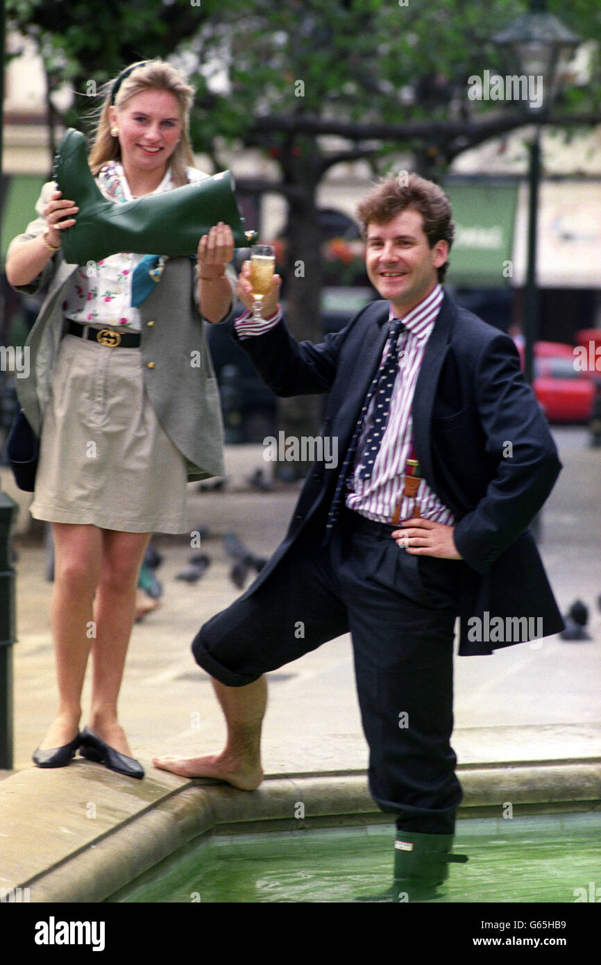 Le courtier d'assurance Rupert Murray, 26 ans, célèbre sa sélection comme Harpers & Queen Sloane Ranger de l'année 1991, avec du champagne d'un wellie vert versé par sa petite amie Becky Bones à Sloane Square, Londres. Banque D'Images