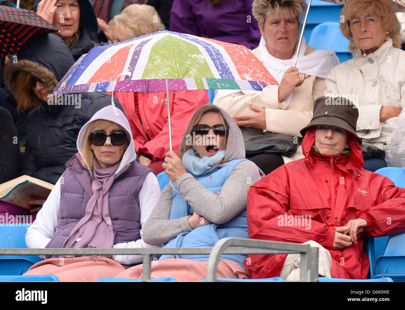 Les spectateurs se réfugient sous la pluie, tandis que le jeu est suspendu le deuxième jour des Championnats AEGON au Queen's Club de Londres. Banque D'Images