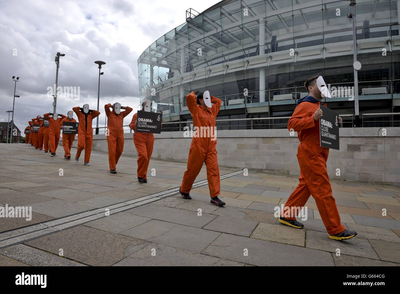 Les manifestants d'Amnesty International, vêtus de combinaisons et de masques orange, ont des pancartes demandant que le président des États-Unis, Barack Obama, ferme Guantanamo, alors qu'ils se rassemblent devant le front de mer de Belfast, avant le sommet du G8. Banque D'Images