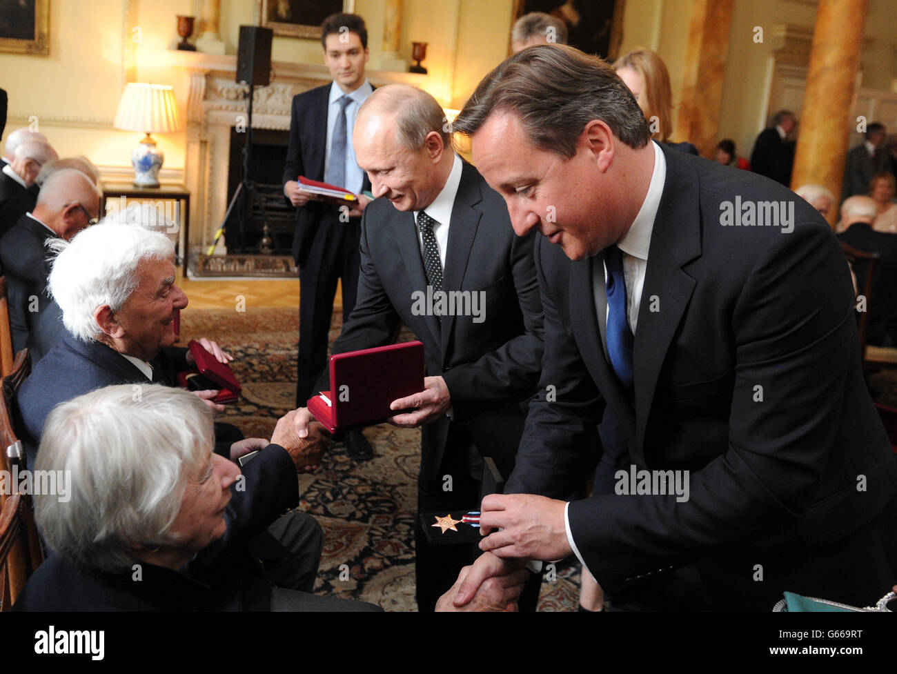 Le Premier ministre David Cameron (à droite) et le président russe Vladimir Poutine (au centre) lors d'une cérémonie pour remettre la médaille russe Ushakov aux anciens combattants de convoi de l'Arctique, au 10 Downing Street, Londres. Banque D'Images