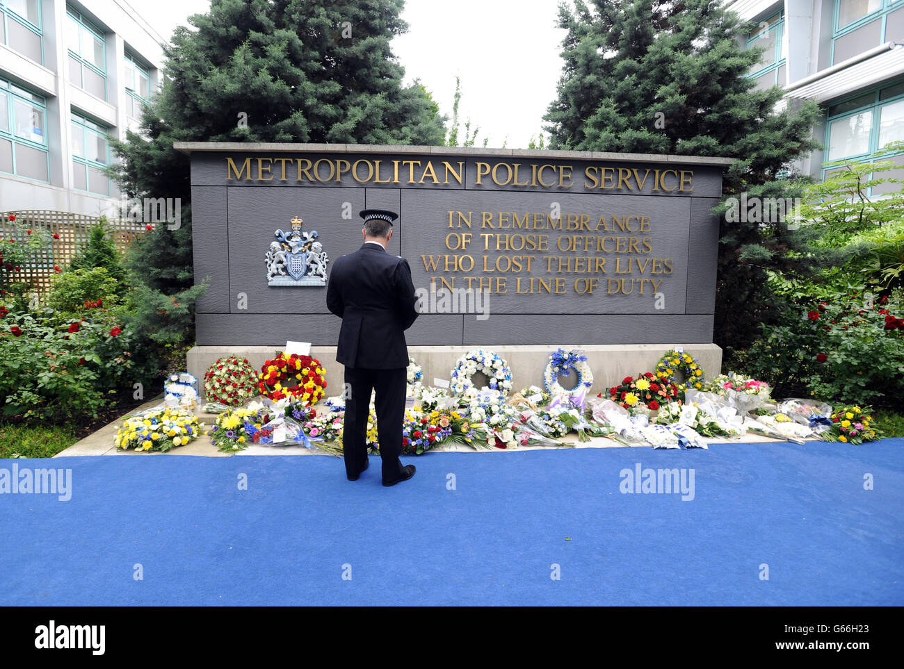 Un officier de police métropolitaine regarde les couronnes laissées en hommage à plus de 650 officiers qui sont morts en service depuis la formation du MPS en 1829, à la suite de la cérémonie du souvenir du Metropolitan police Service (MPS), dans le jardin commémoratif du quartier général de formation du Metropolitan police Peel Centre à Hendon, Colindale, Londres. Banque D'Images