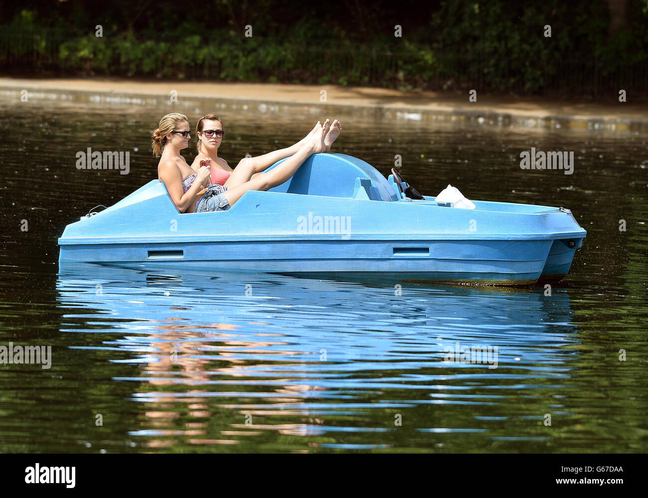 Quelques filles flottent sur le lac Serpentine dans le centre de Londres de Hyde Park, alors que le temps chaud frappe la capitale. Banque D'Images