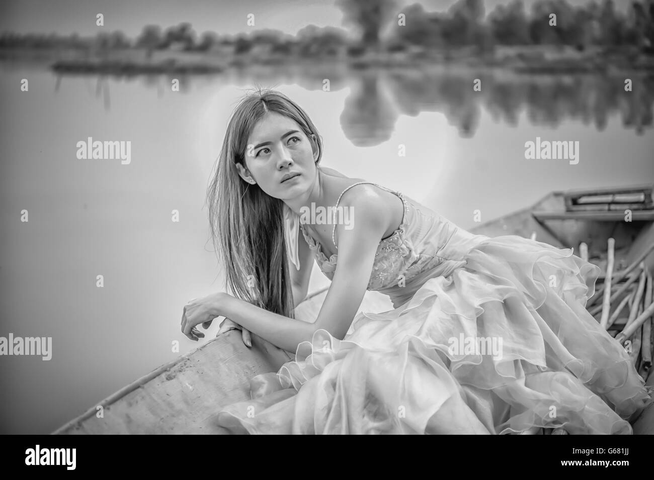 Portrait de l'Asie belle femme en robe jaune assis sur le bateau, image en noir et blanc Banque D'Images