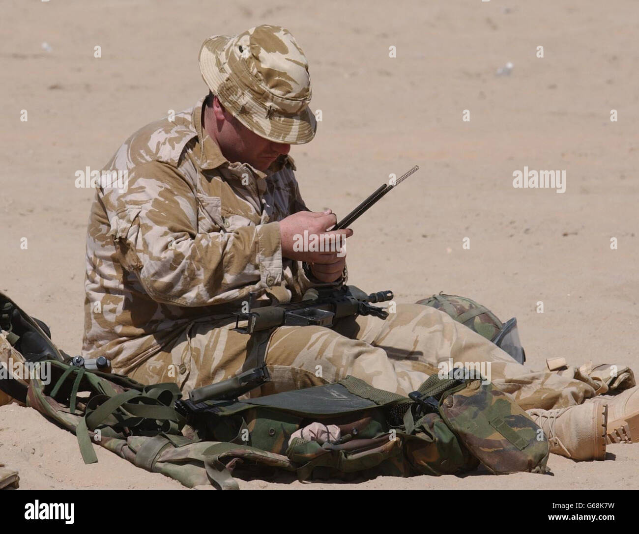 Un membre de la Royal Scots Dragoon Guards inspecte son équipement dans le désert du Koweït, avant une éventuelle action militaire. Banque D'Images