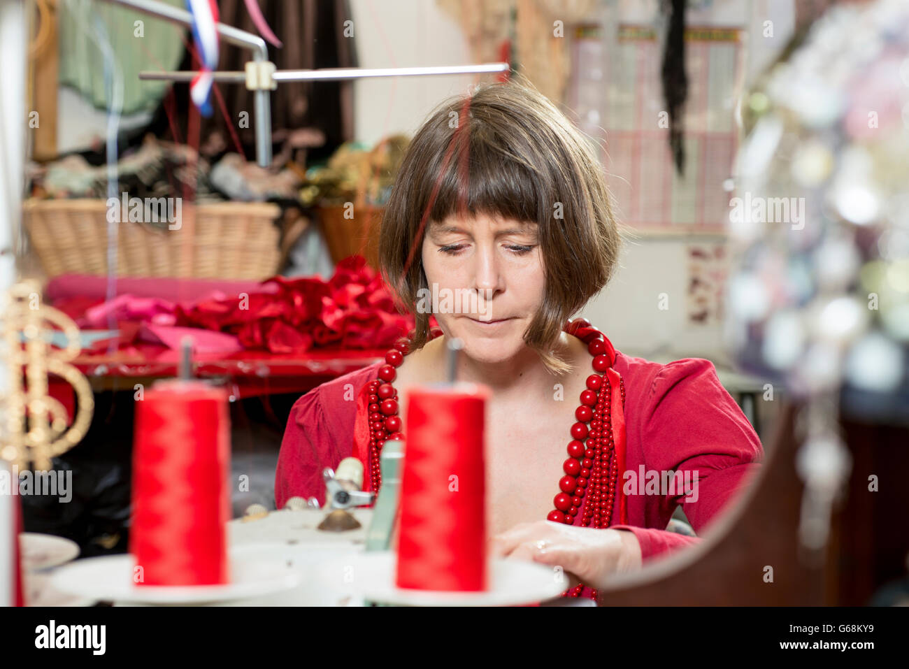 Une couturière en rouge travailler avec une machine à coudre Banque D'Images