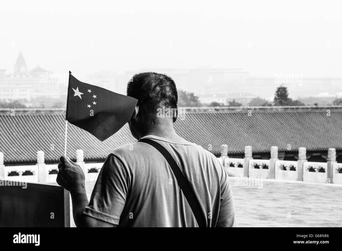 Vue arrière d'hommes tenant un drapeau de la Chine contre les toits de la Cité Interdite Banque D'Images