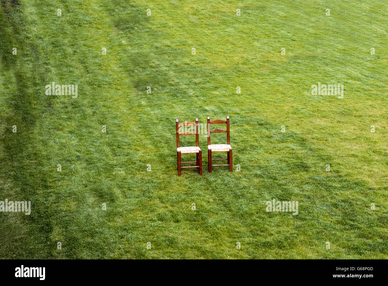 Une paire de chaises en bois solitaire sur l'herbe verte Banque D'Images