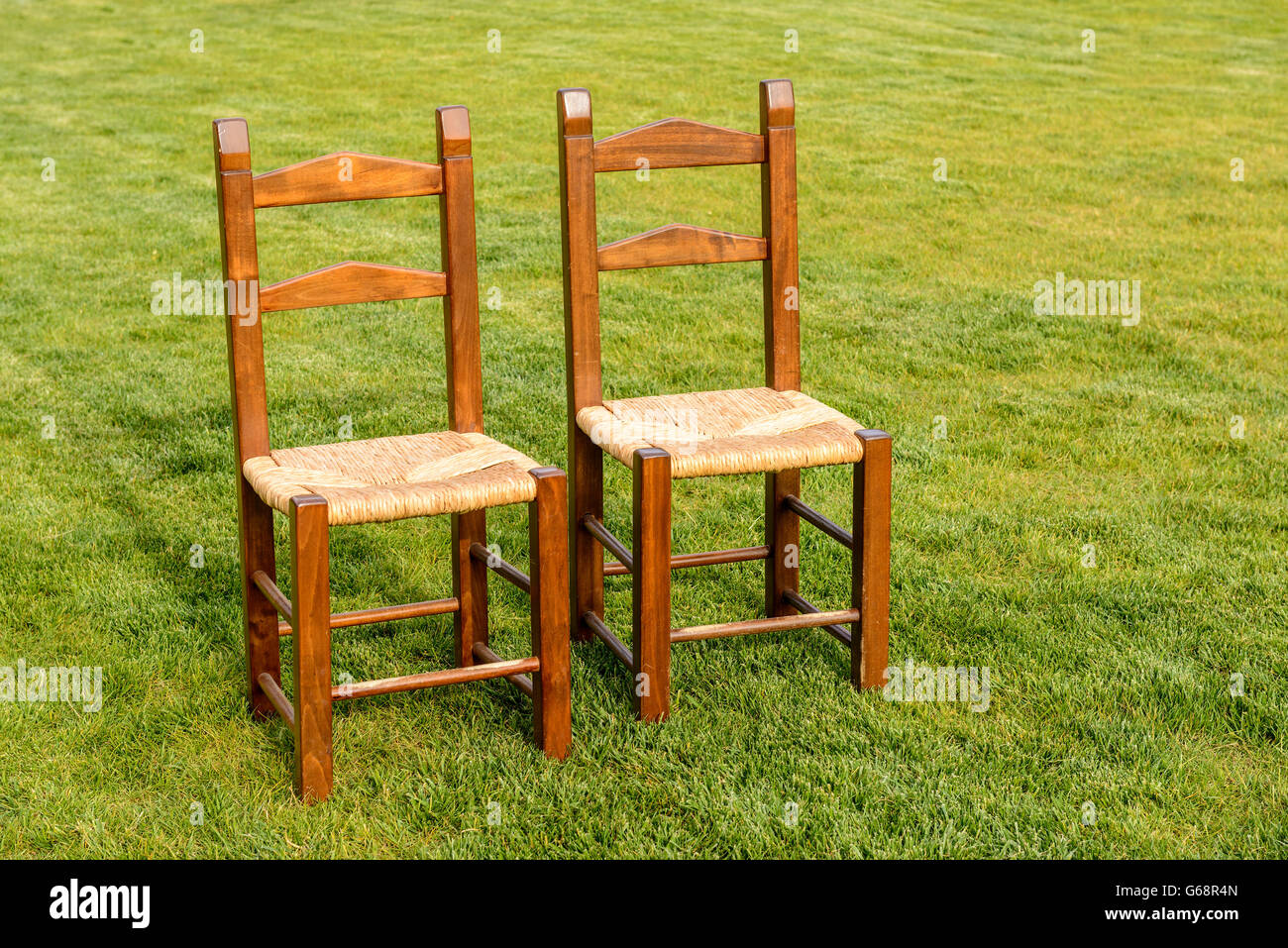 Paire de chaises en bois solitaire sur l'herbe verte Banque D'Images