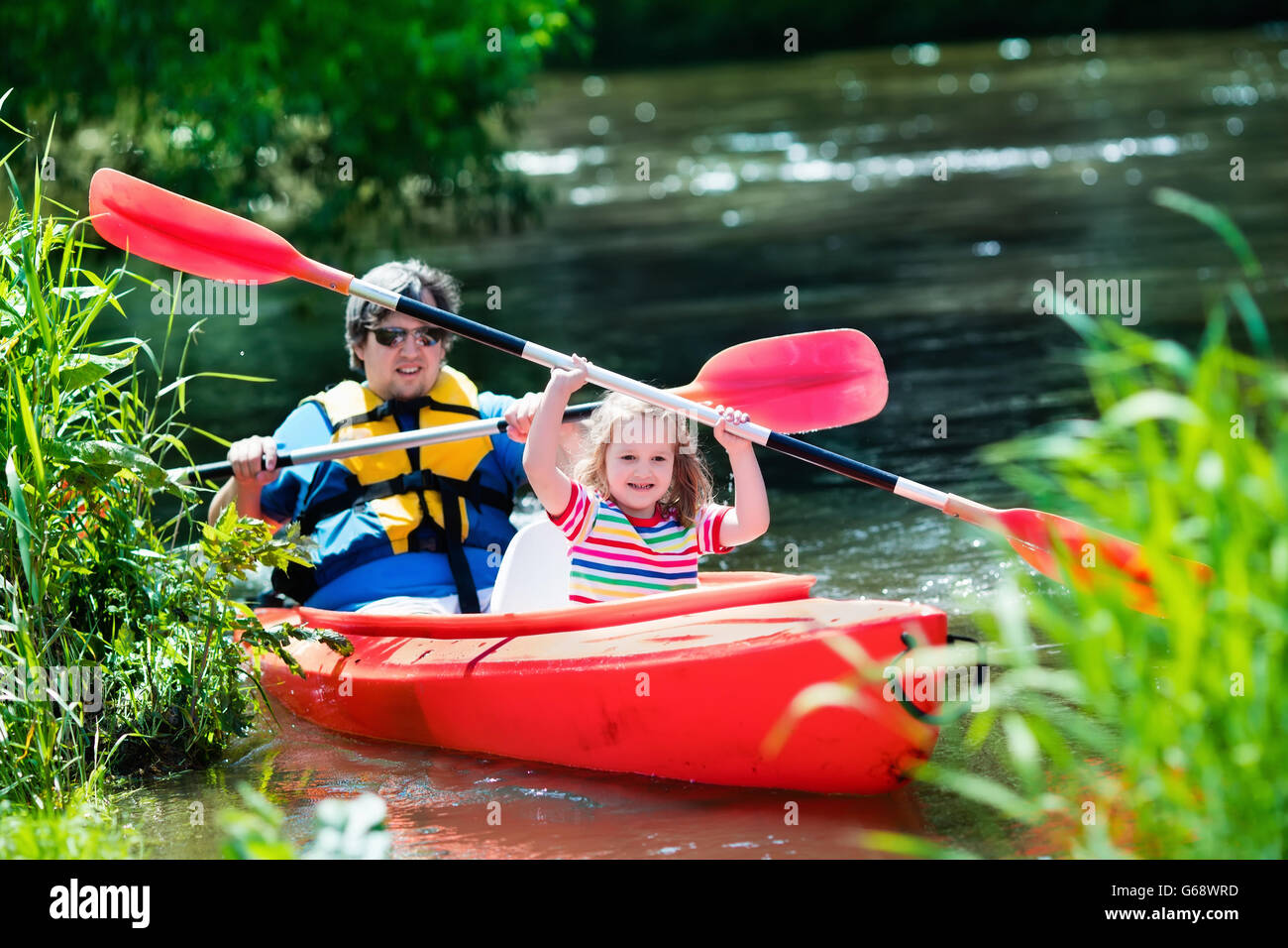 Famille sur les kayaks et canoës tour. La mère et l'enfant dans la pagaie  kayak dans une rivière sur une journée ensoleillée. En été, les enfants du  camp de sport Photo Stock -