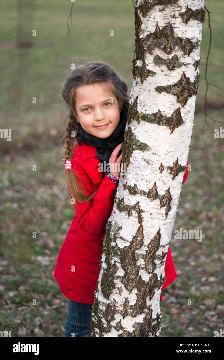 Fille cachée derrière la tige des arbres de bouleau Banque D'Images