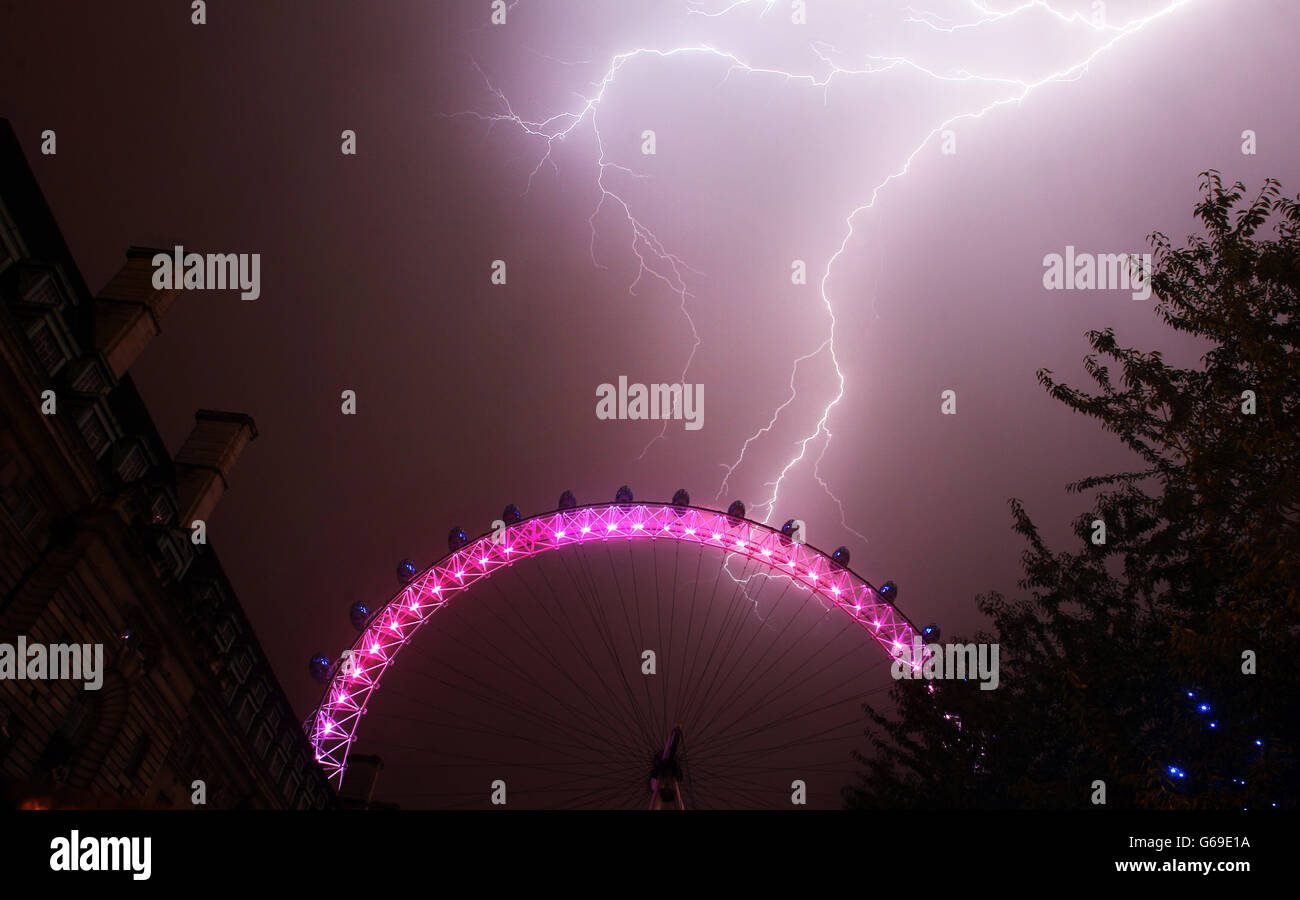 La foudre frappe derrière le London Eye dans le centre de Londres qui est de couleur rouge, blanc et bleu pour marquer la naissance d'un bébé garçon, à 16h24 hier au Duc et Duchesse de Cambridge à l'hôpital St Mary's. Banque D'Images