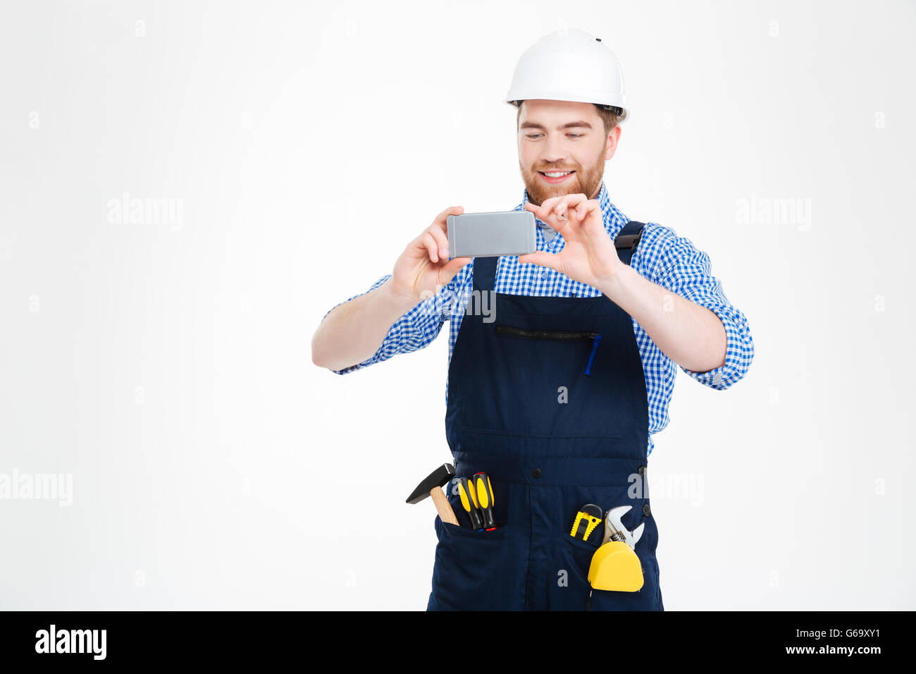 Happy young builder en utilisant des photos de casque de smartphone Blackberry Banque D'Images
