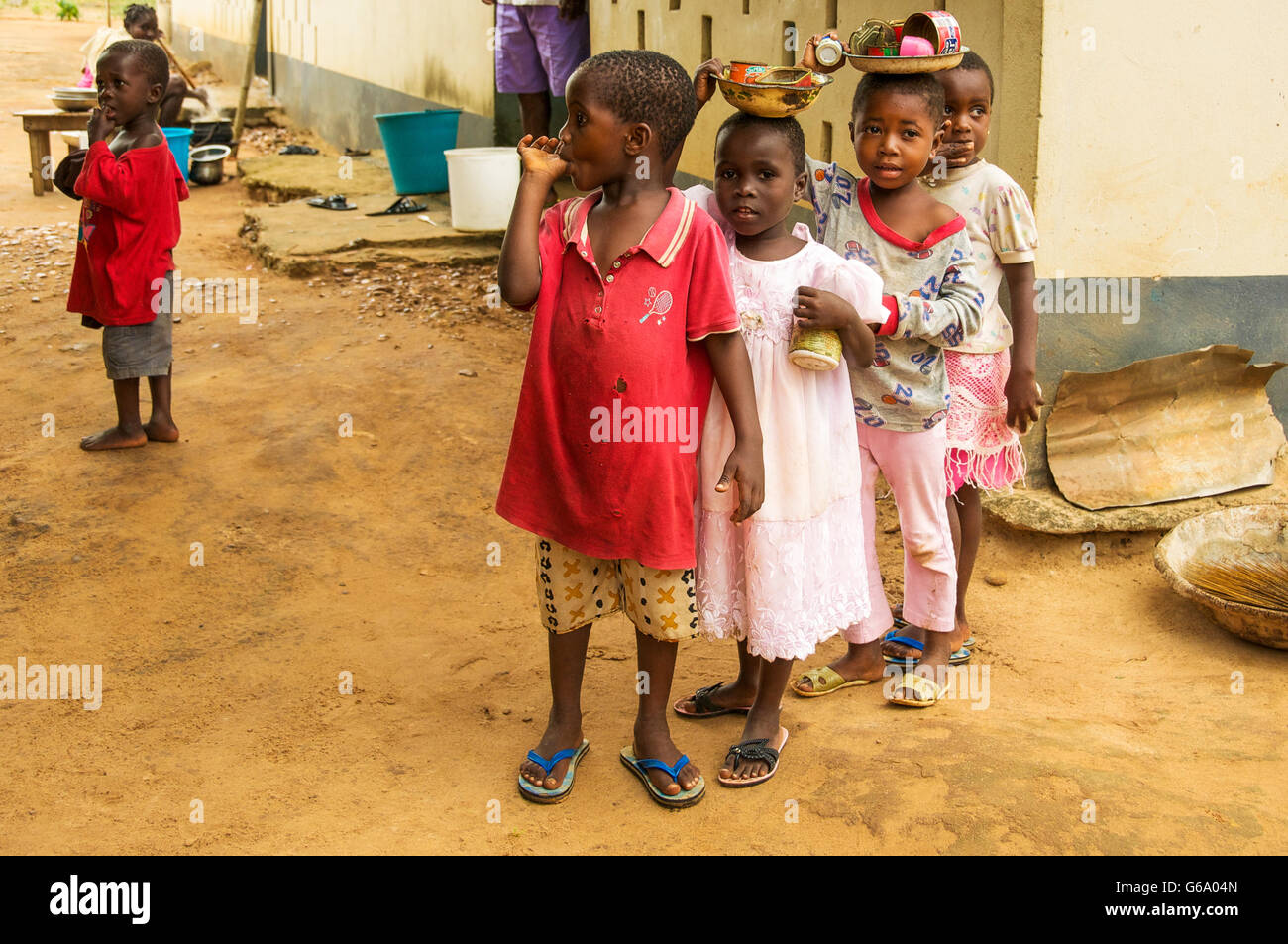 Les enfants africains à jouer avec les boîtes de conserve rouillée dans village pauvre de Ghana Banque D'Images