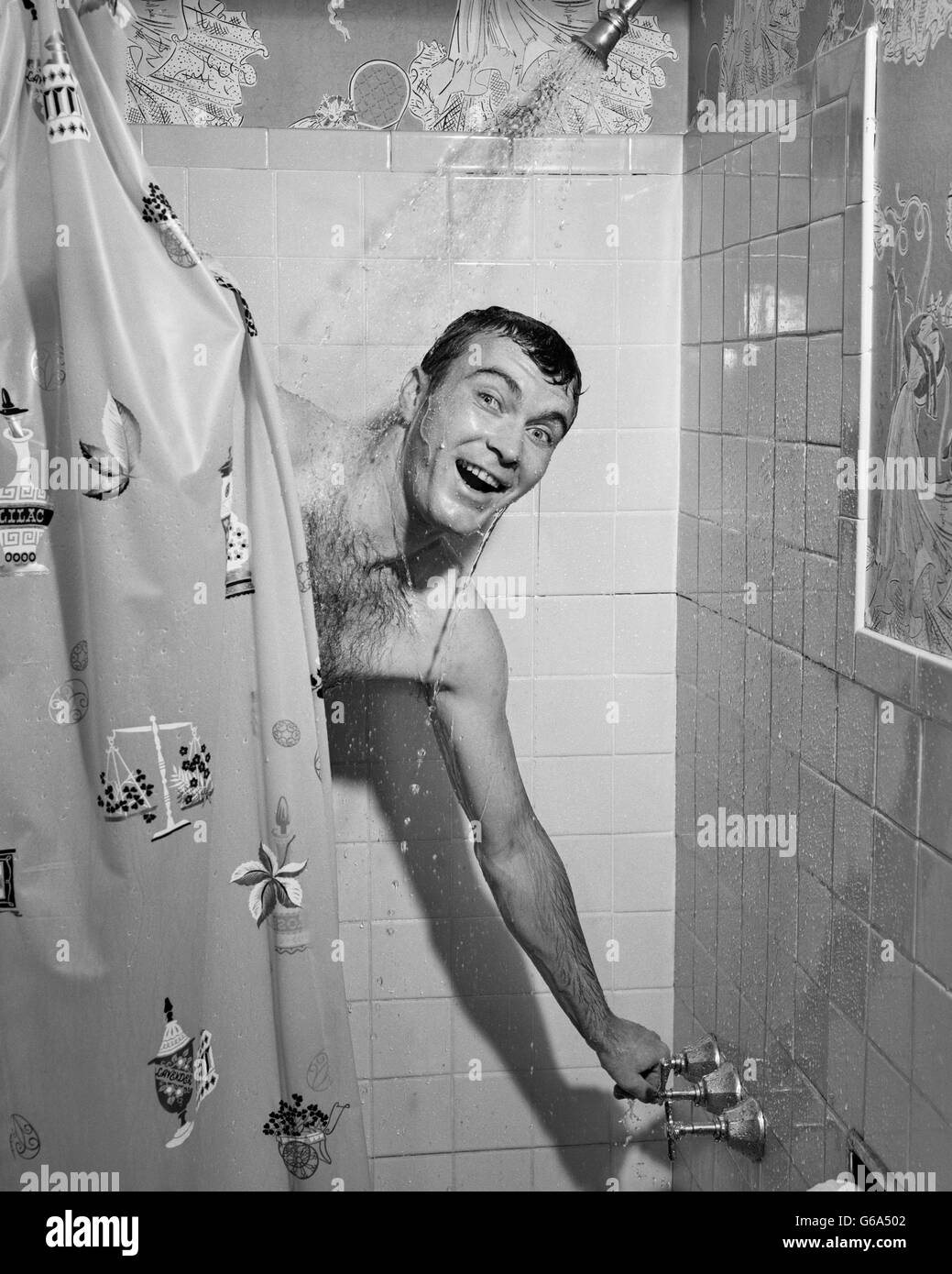 Années 1950 L'HOMME À TOURNER SUR L'EAU ET DE DOUCHE rideau de douche fermée tirant Banque D'Images