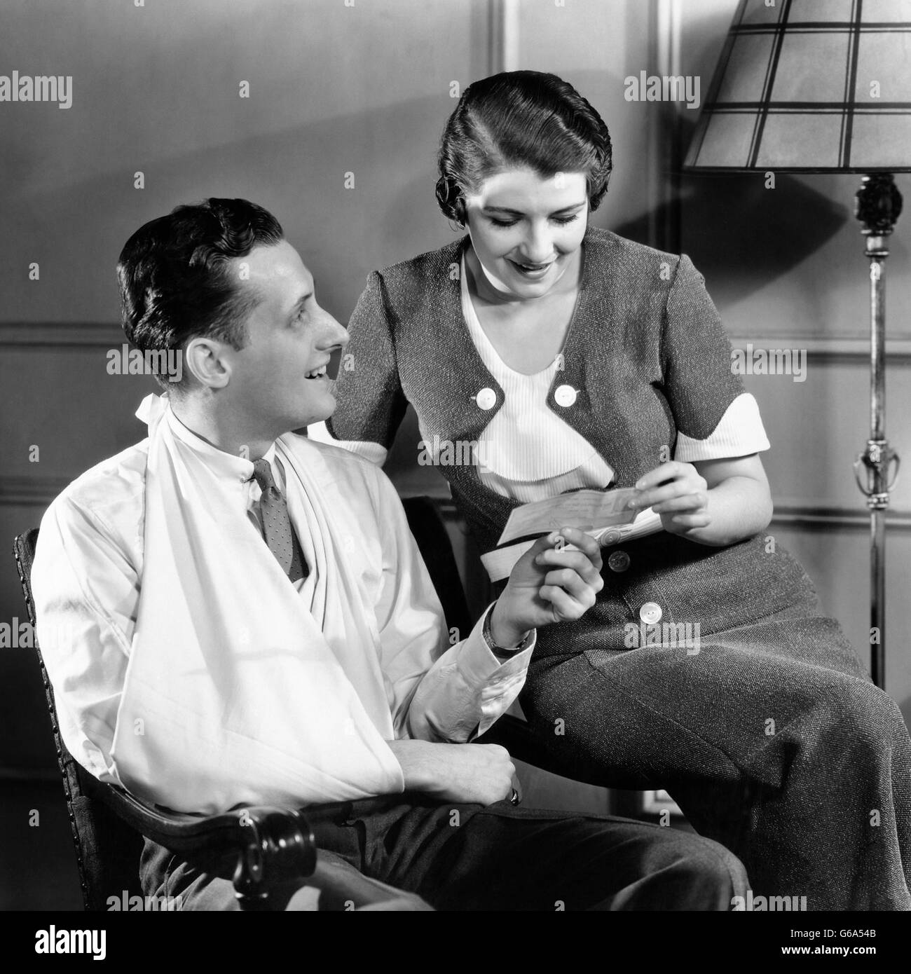1930 COUPLE femme détenant une police d'assurance Consultez le man avec le bras en écharpe blessés Banque D'Images