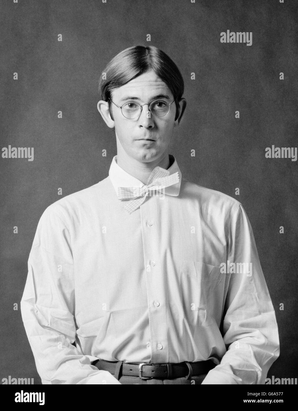 1970 PORTRAIT GEEKY DORKY GIROFLÉE timide jeune homme portant des lunettes, chemise blanche et chapeau Banque D'Images