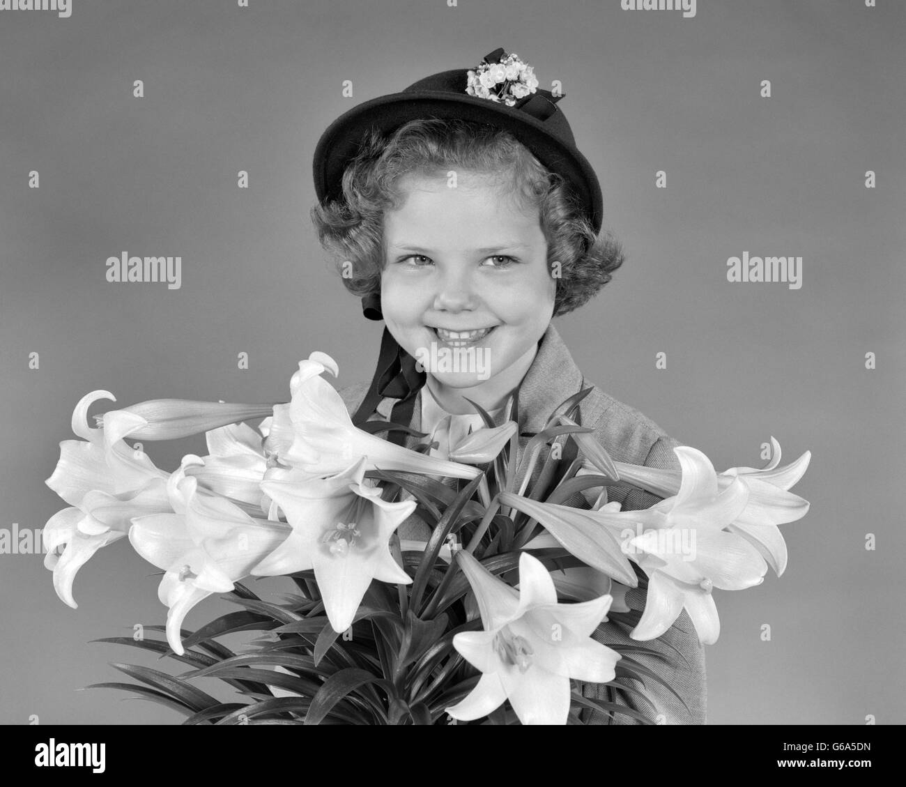 1950 PORTRAIT SMILING GIRL HOLDING EASTER LILIES Banque D'Images