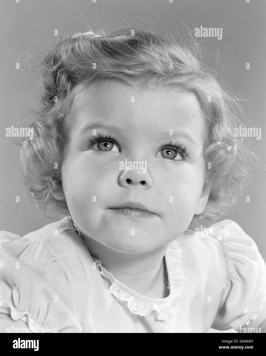 1950 SMILING LITTLE GIRL PORTRAIT TODDLER LOOKING UP AT CAMERA Banque D'Images