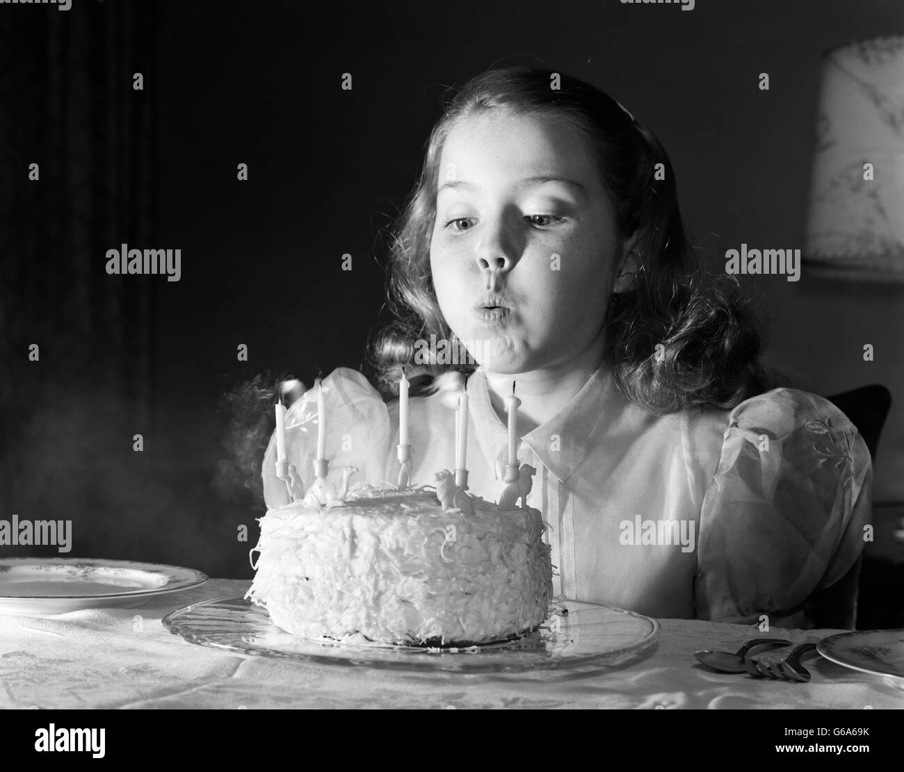 1950 GIRL IN PARTY DRESS BLOWING OUT CANDLES ON CAKE AVEC 5 BOUGIES Banque D'Images