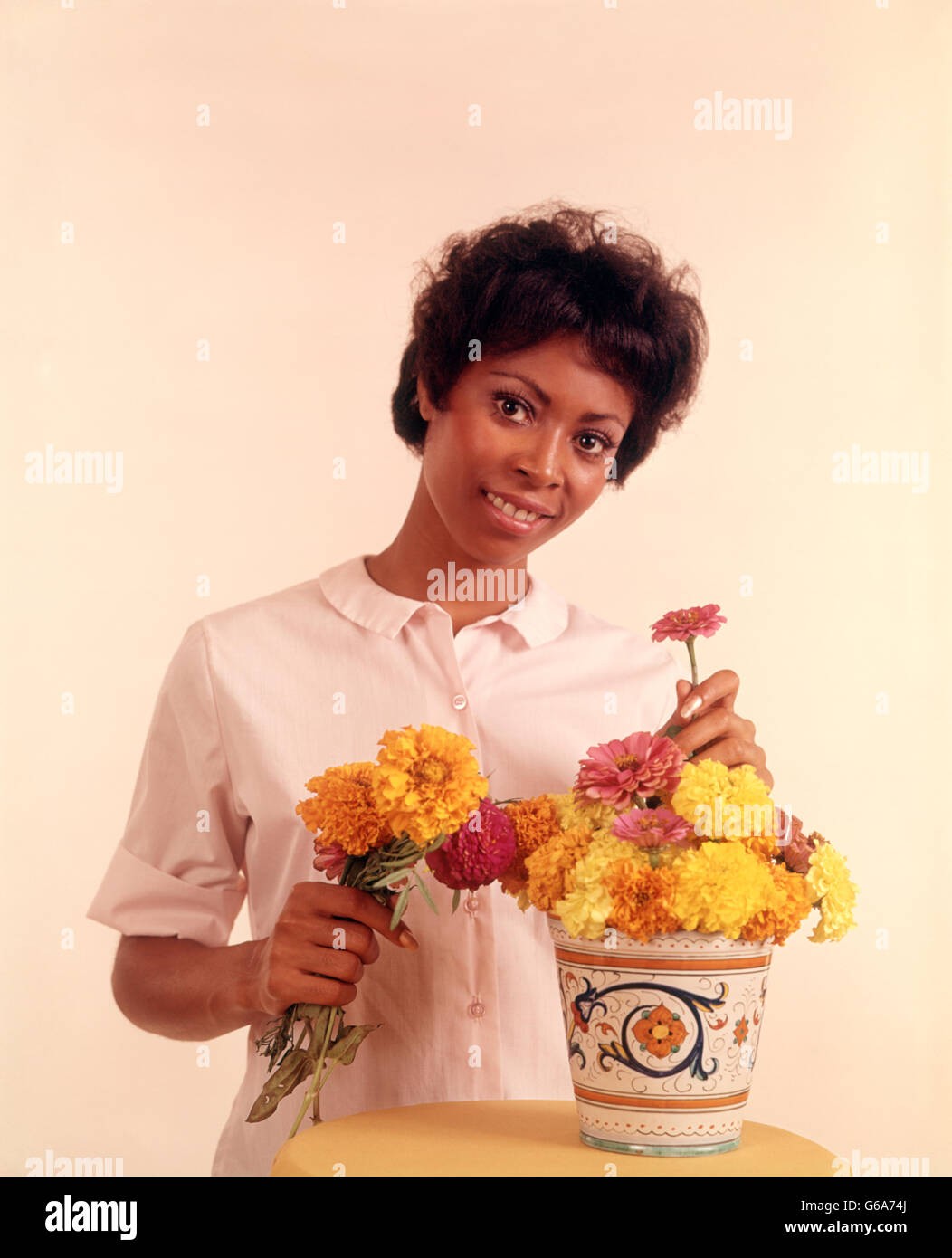 1970 PORTRAIT SMILING AFRICAN AMERICAN WOMAN ARRANGING FLOWERS Banque D'Images