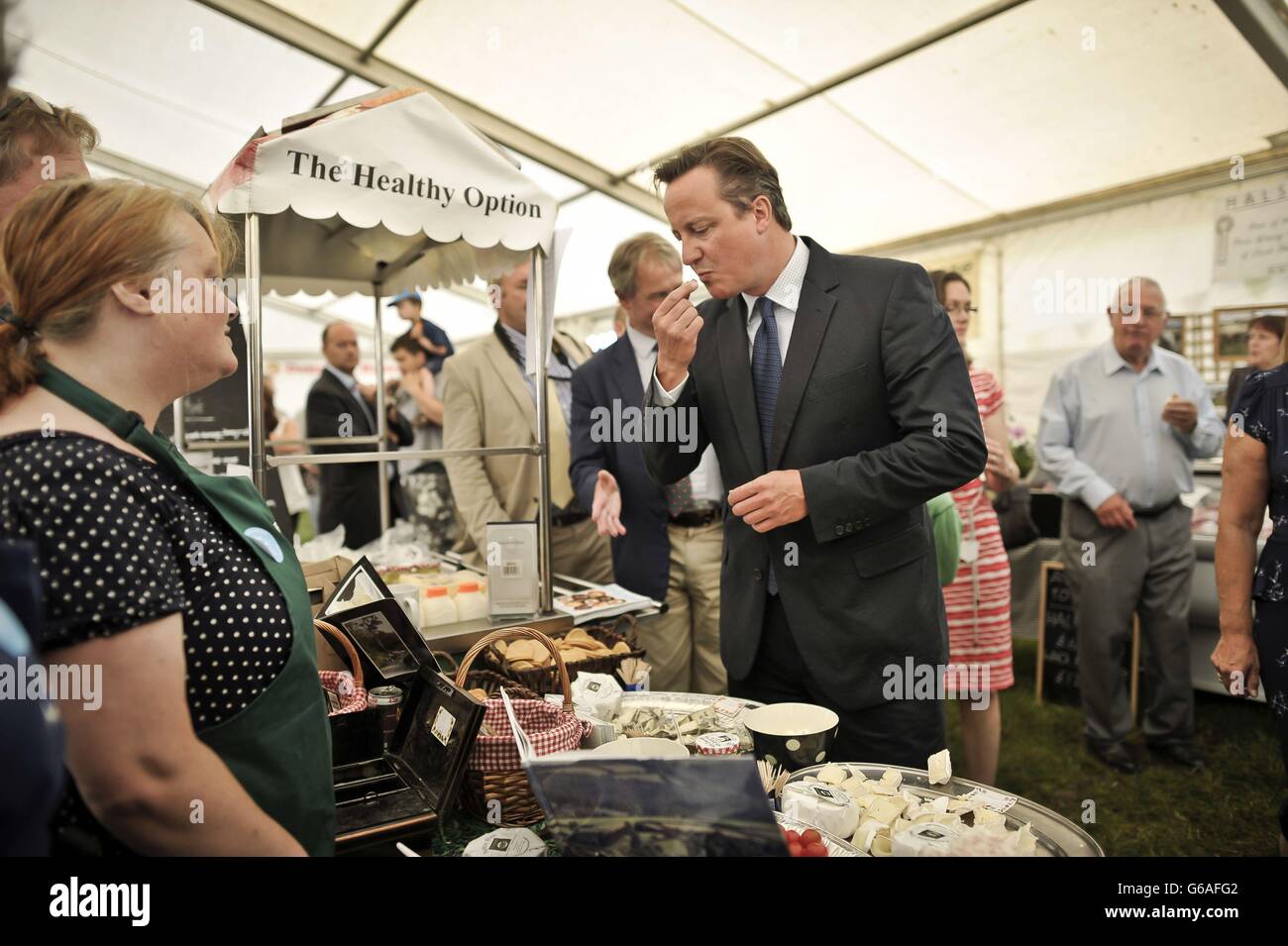 Le Premier ministre David Cameron goûte du fromage lorsqu'il discute avec les détenteurs de stalle lors d'une visite au salon agricole du North Devon, à la ferme Barton, à Umberleigh, dans le Devon. Banque D'Images