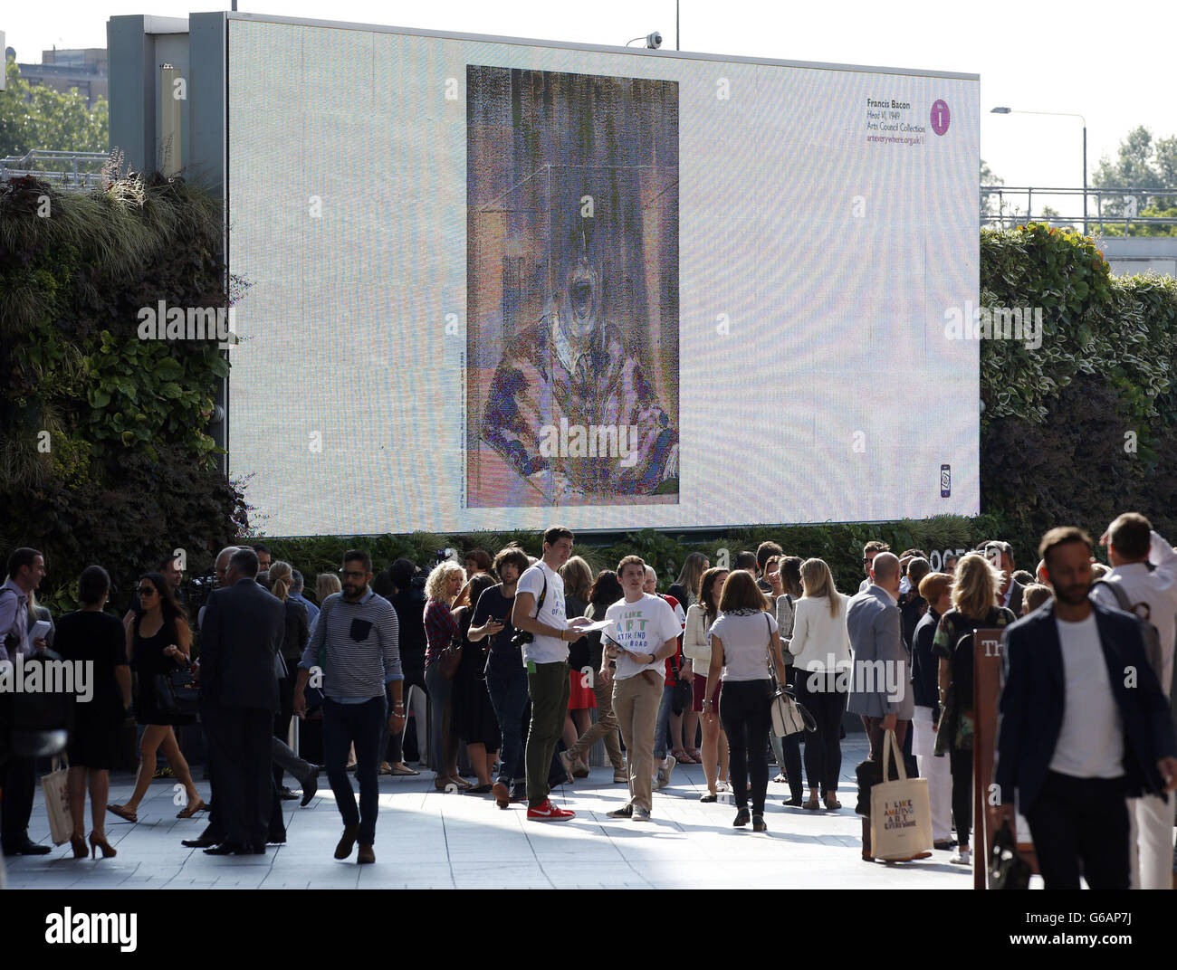 Les acheteurs passent par une reproduction numérique de la « tête » de Francis Bacon affichée sur le panneau d'affichage extérieur du centre commercial Westfield, Shepherd's Bush, Londres, pour lancer Art Everywhere. Banque D'Images
