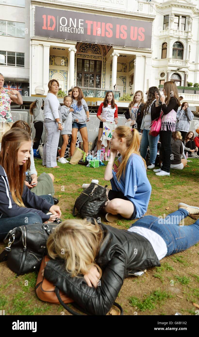 Jeunes filles certaines qui ont campé dehors depuis dimanche soir, se réveiller à Leicester Square, centre de Londres en attendant la première de ce soir du film One Direction: This US in central London. Banque D'Images