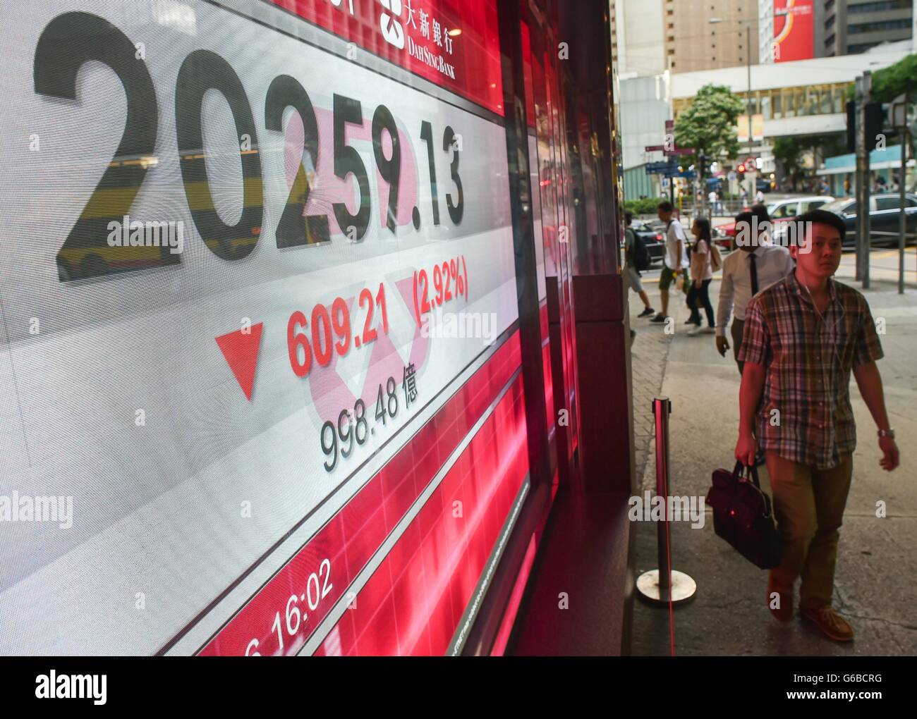 Hong Kong, Chine. 24 Juin, 2016. Les piétons passent devant un écran affichant l'indice Hang Seng, chiffres de clôture à Hong Kong, Chine du sud, le 24 juin 2016. Les stocks de Hong Kong a pris fin le vendredi avec le plus faible indice de référence Indice Hang Seng, chute de 2,92 %, ou 609,21 points pour terminer à 20 259,13 points. © Lui Siu Wai/Xinhua/Alamy Live News Banque D'Images