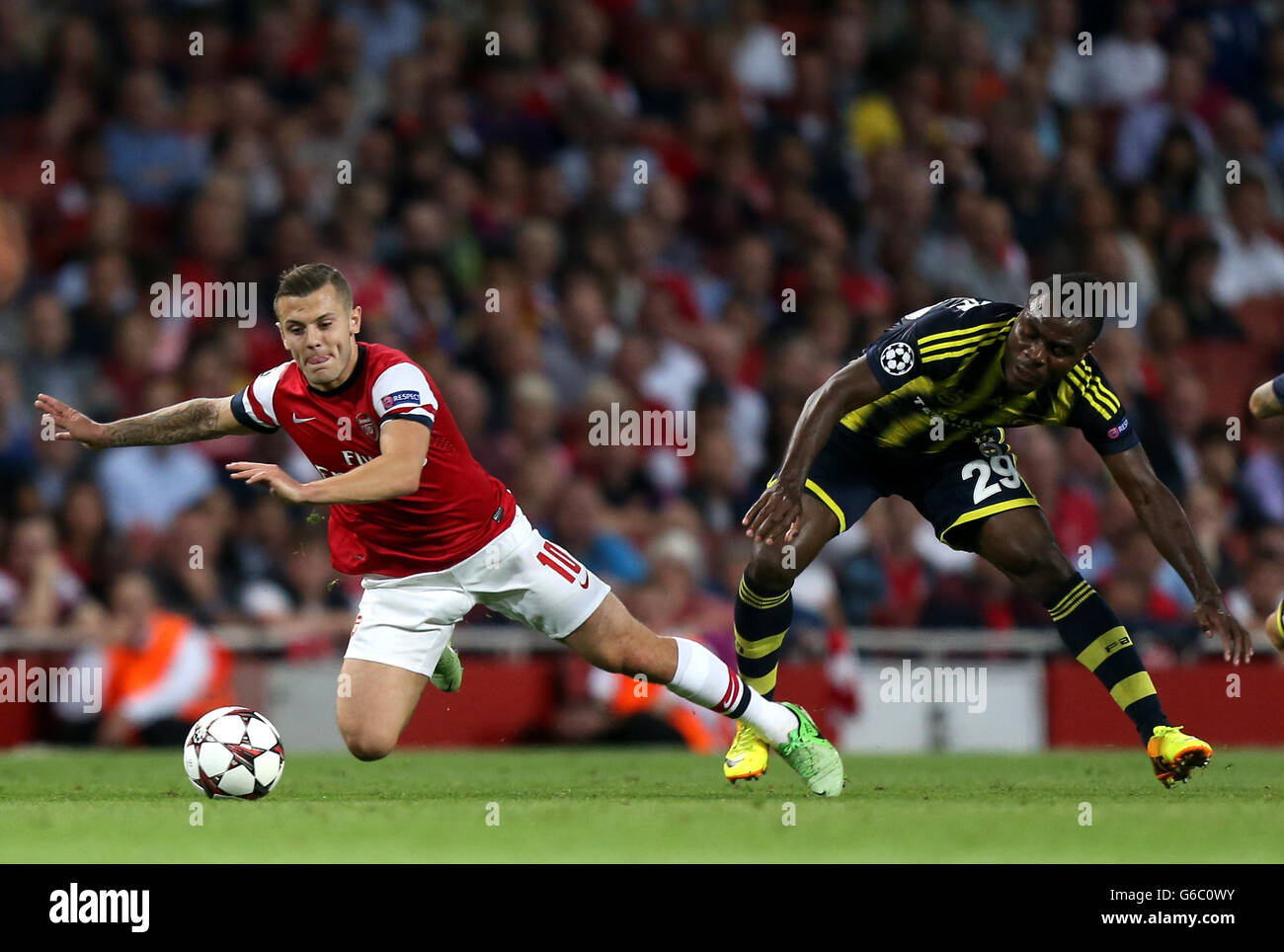 Jack Wilshere d'Arsenal (à gauche) est envoyé sous le défi d'Emmanuel Emenike de Fenerbache lors de la Ligue des champions de l'UEFA, Play-off Round, second Leg au stade Emirates, Londres. Banque D'Images